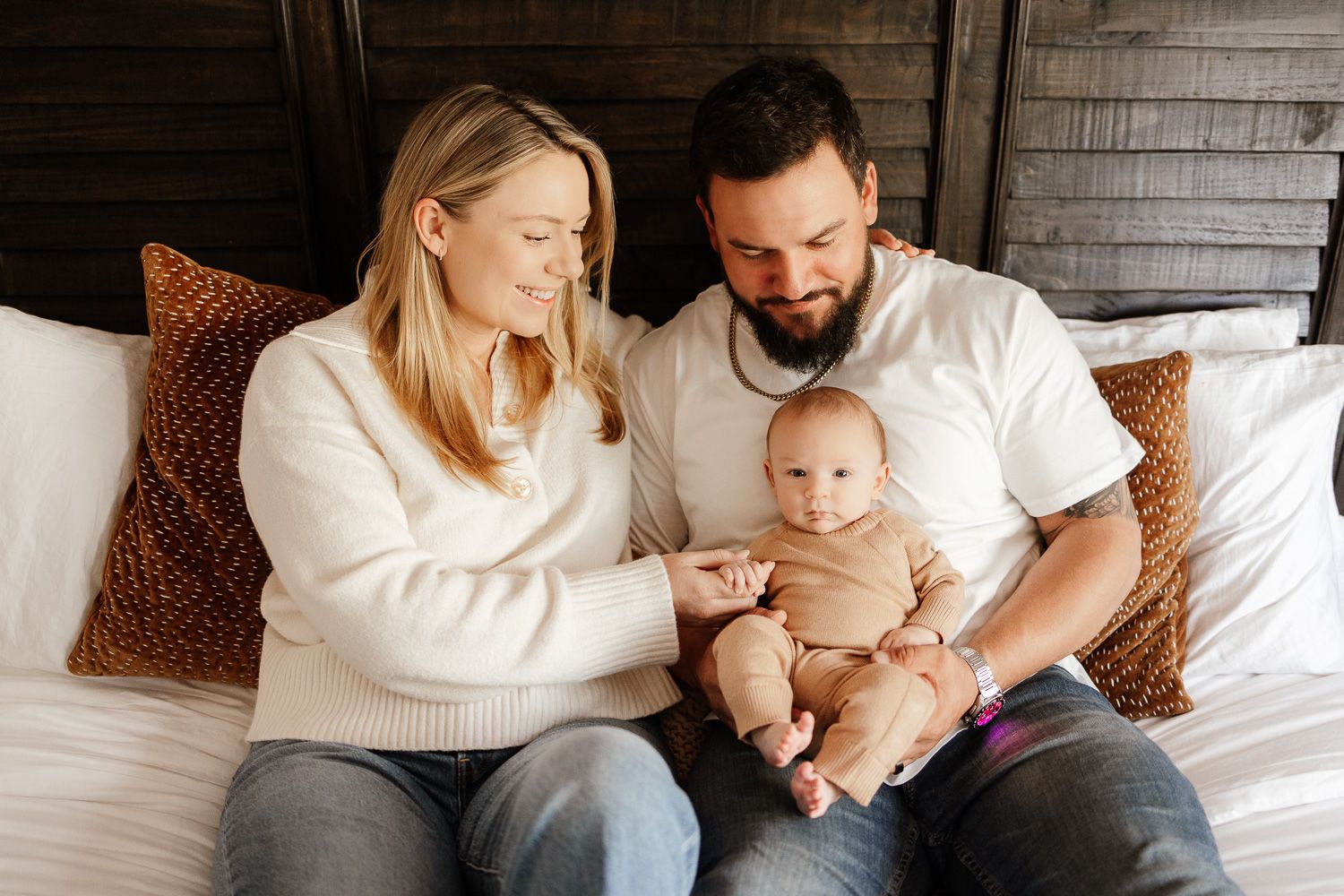 a mom and dad smile at their new baby at their in-home newborn photoshoot