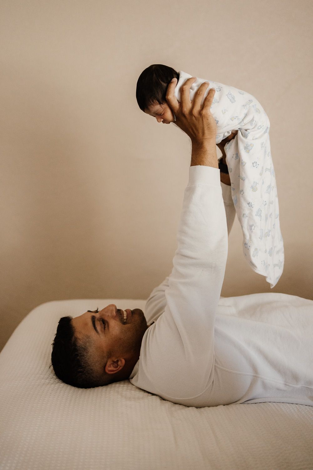 A dad lifts his newborn baby above his head