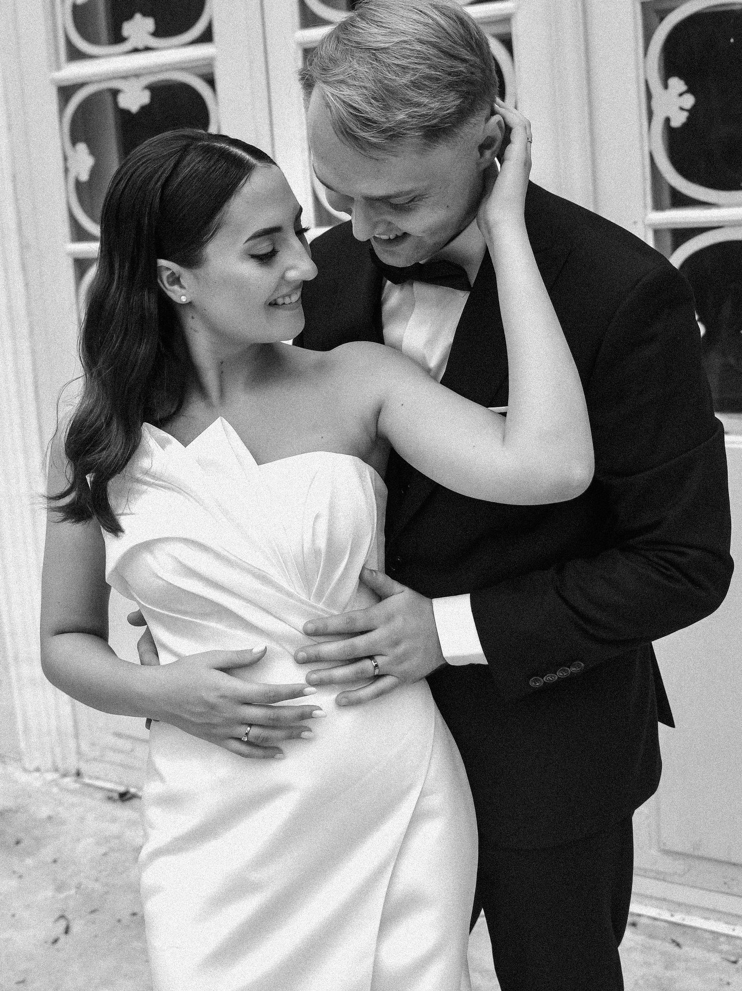 A romantic black and white photo series of a couple embracing during their wedding photoshoot, with the bride in white and groom in black.