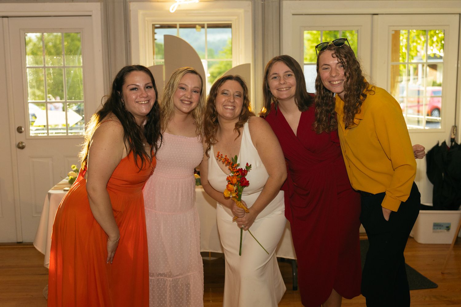 A group of people wearing colorful dresses and outfits pose together at a formal event.