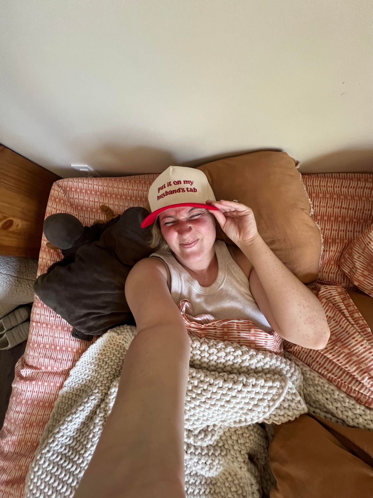 A sequence of photos showing someone resting on a couch with a knitted blanket and wearing a baseball cap.