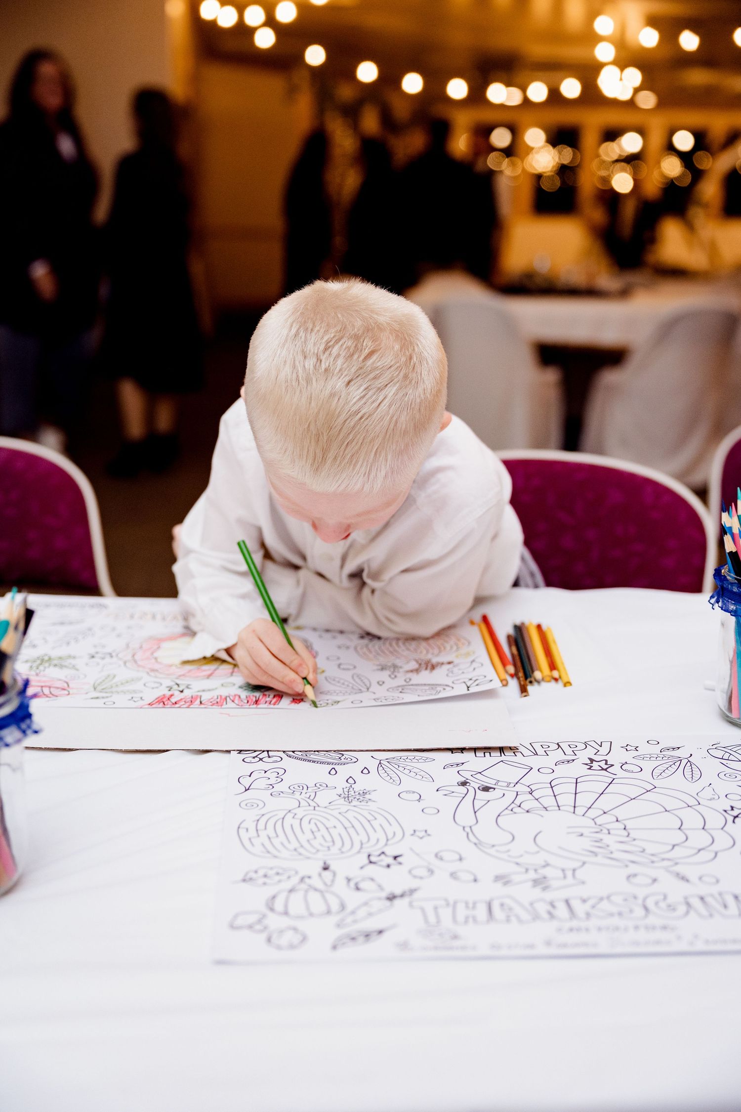 child coloring at kids table at a lively wedding reception