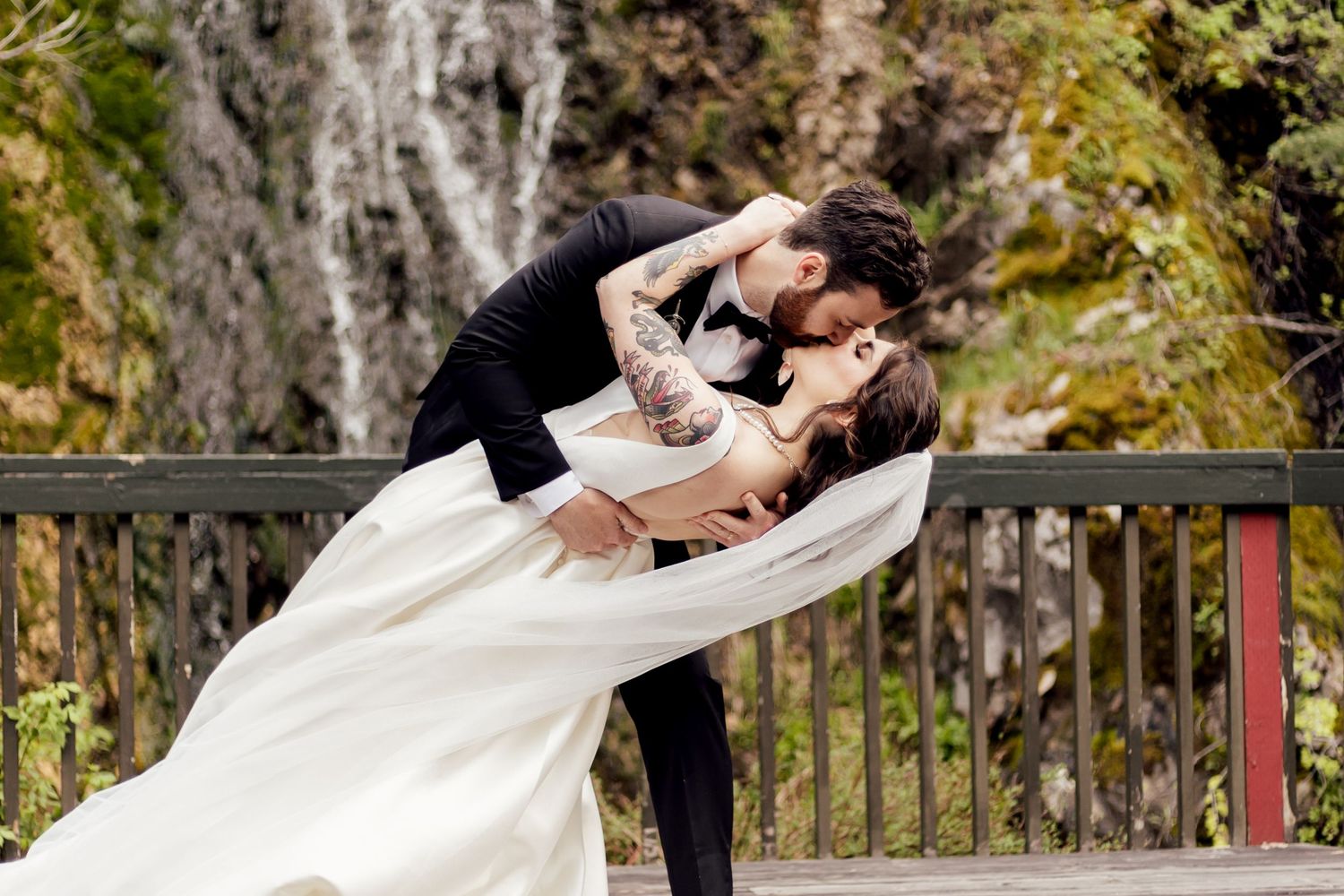 bride and groom kissing in front of a waterfall at missouri wedding