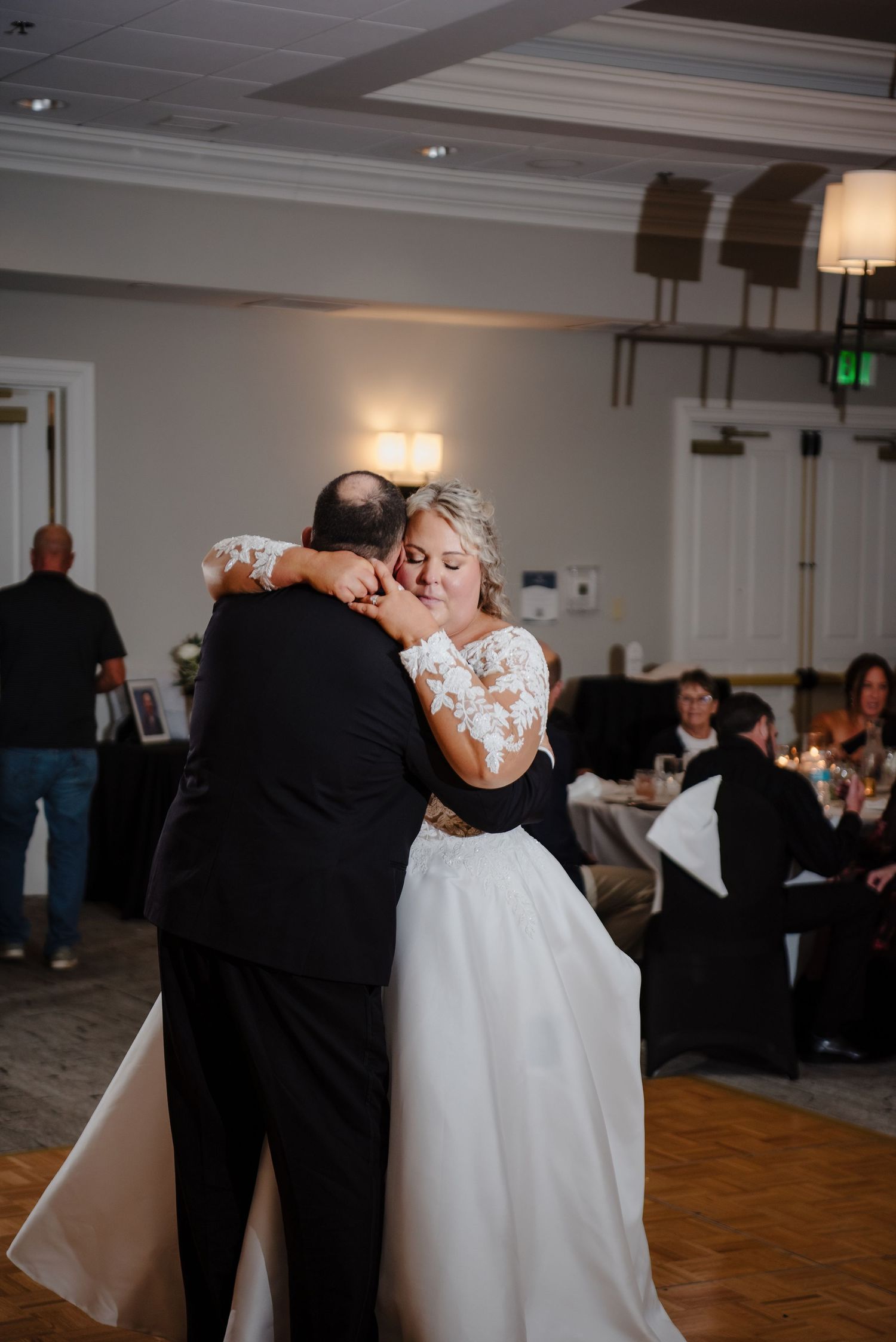 Bride and father share emotional first dance embrace at elegant wedding reception venue.