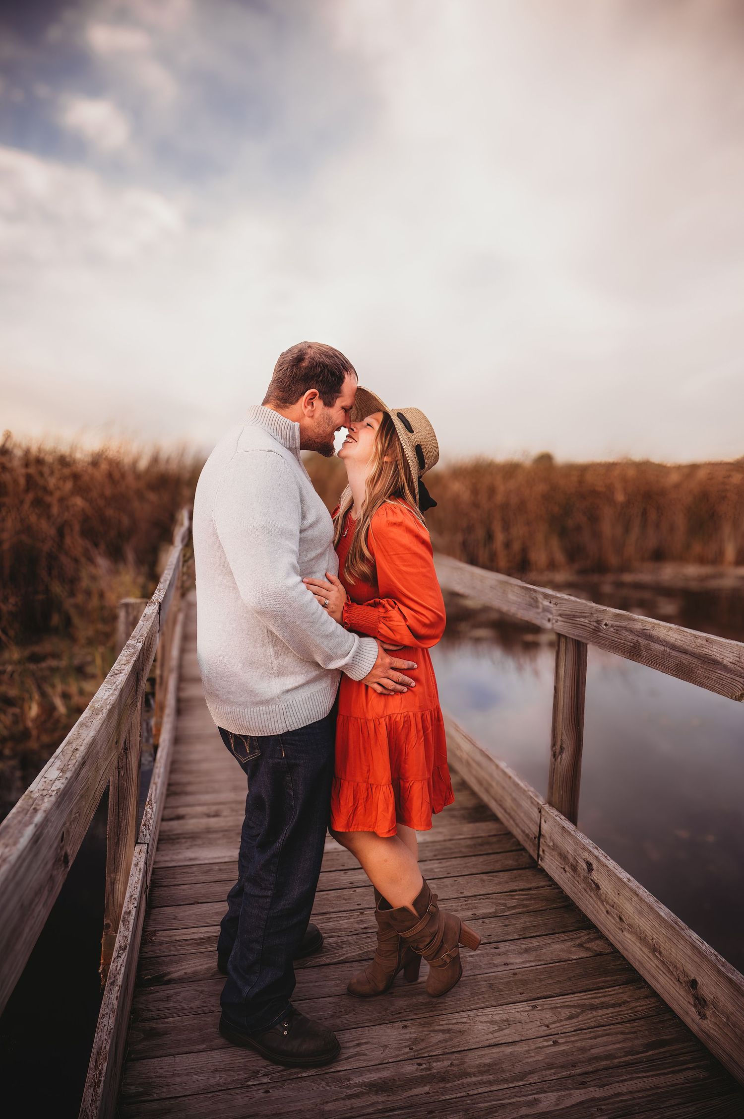 Romantic couple sharing intimate moments on a wooden boardwalk at sunset.