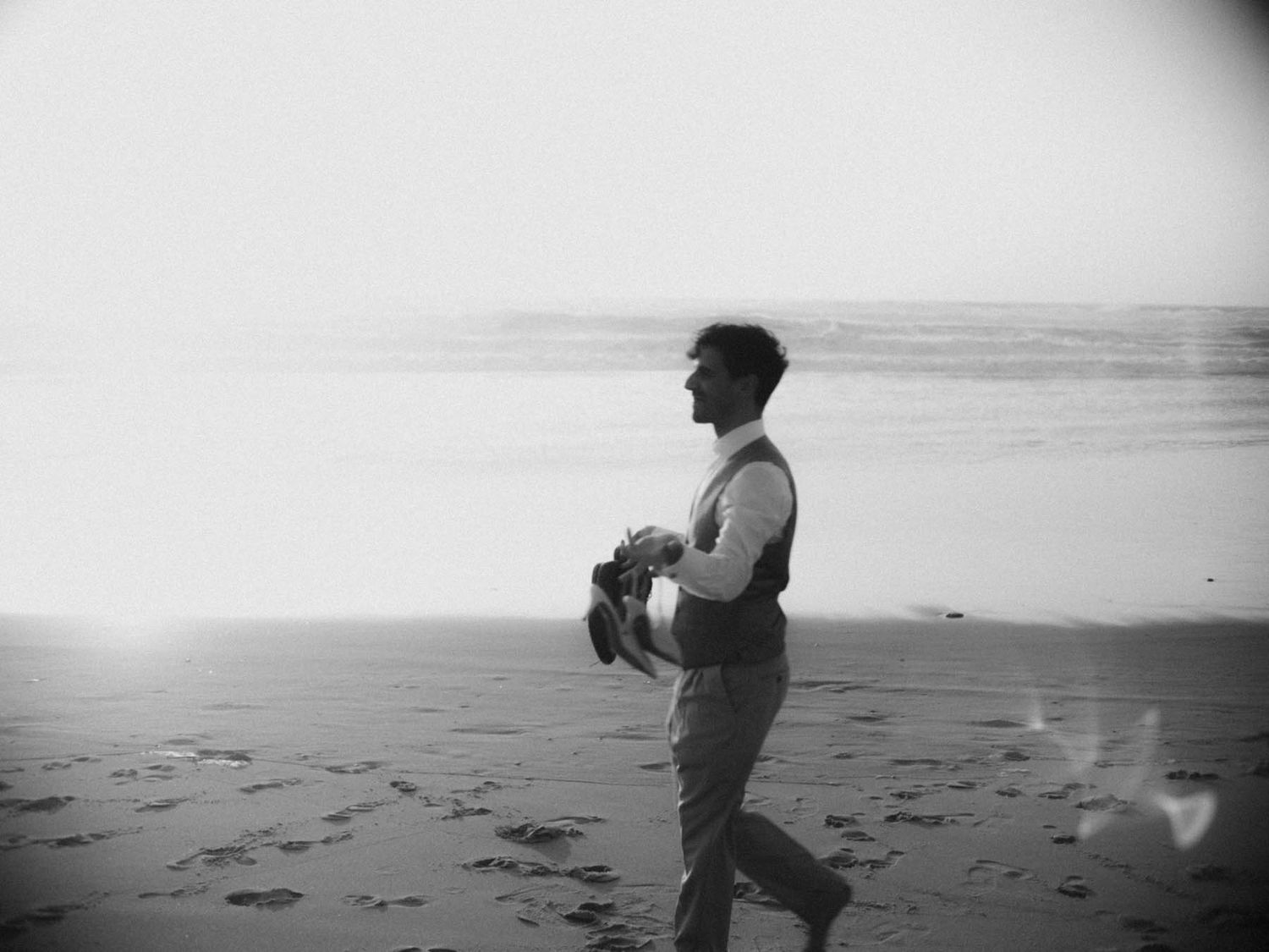 elopement in lisbon portugal groom walking on beach