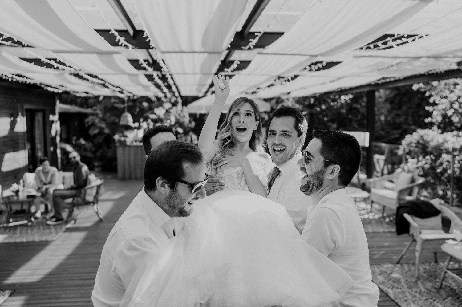 friends lifting the bride during wedding celebration in portugal
