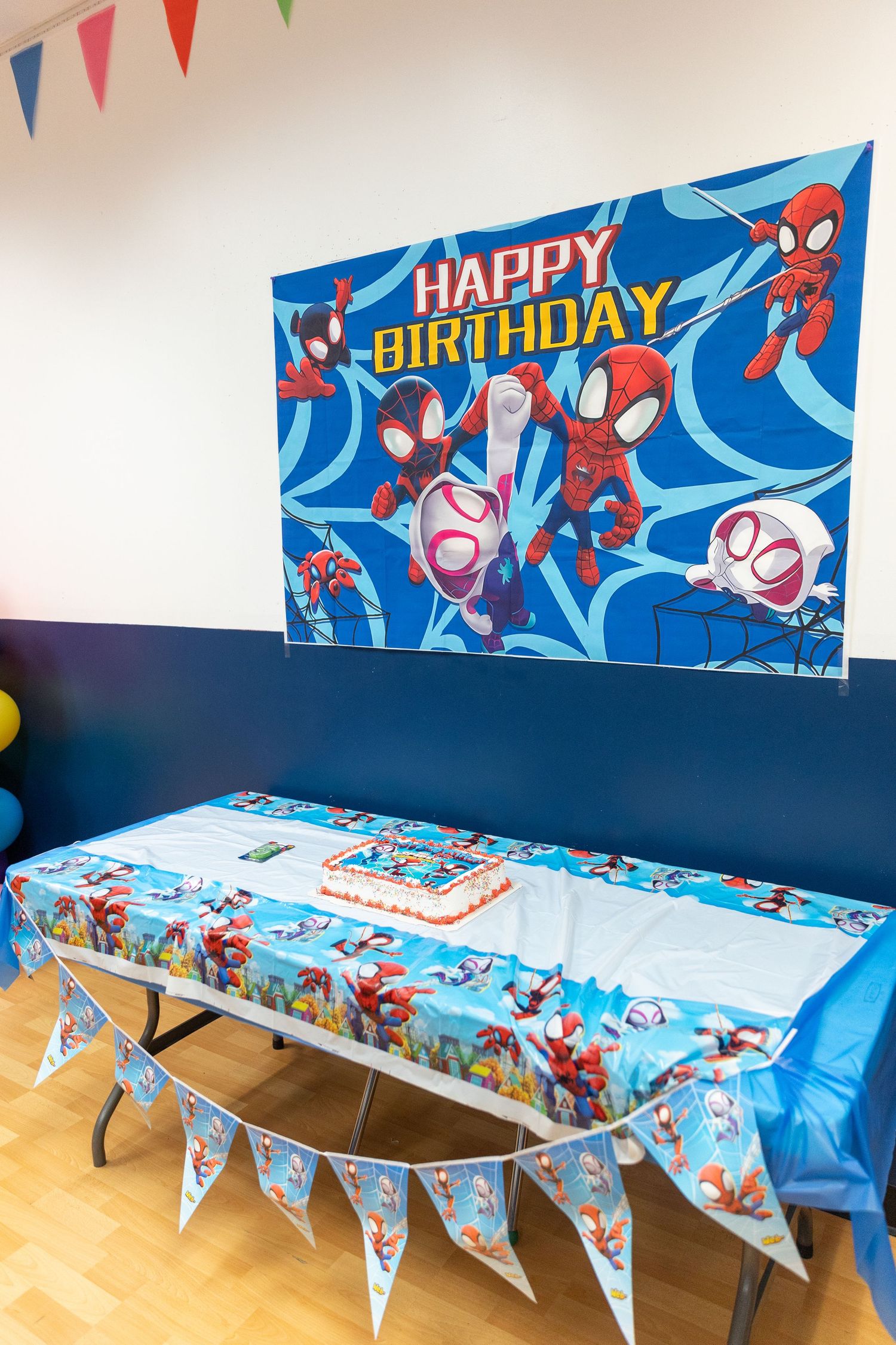 Spiderman themed happy birthday party setup with cake table and banner decoration.
