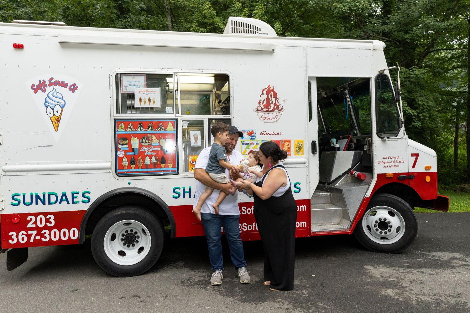 Couple ordering ice cream from a soft serve sundaes food truck outdoors.