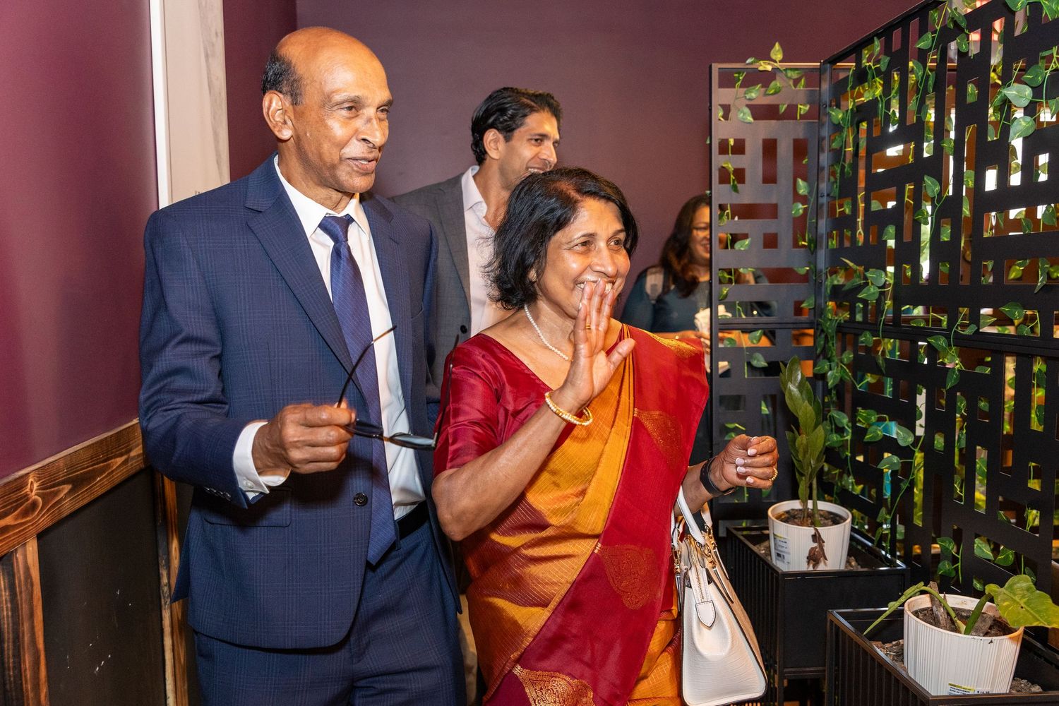 Elderly Indian couple in traditional attire greeting guests at a 75th birthday celebration event.
