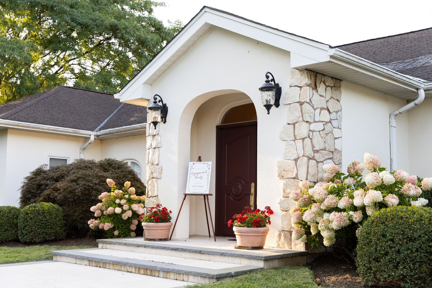 Elegant venue entrance with stone arch, hydrangea flowers and welcome sign.