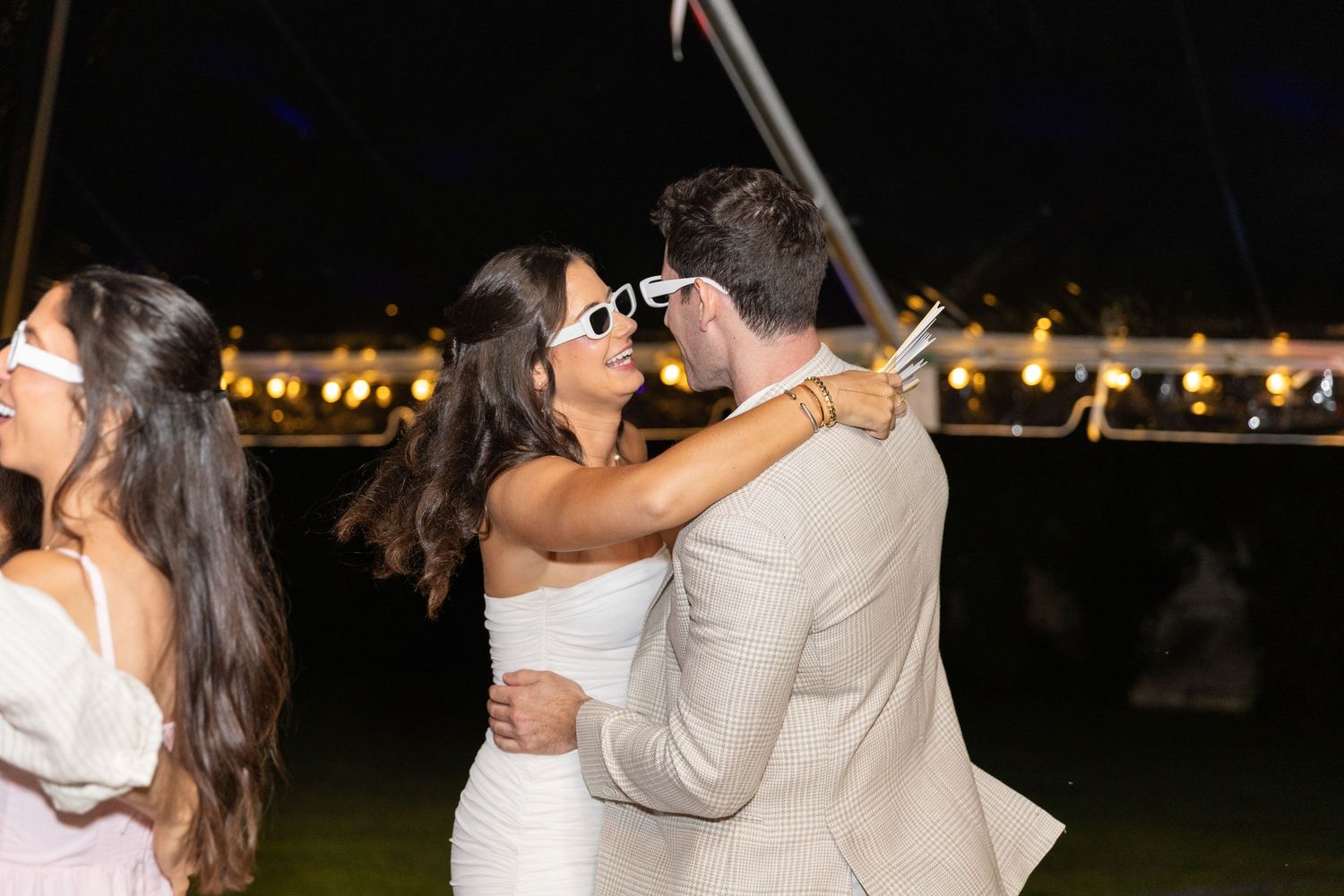 Bride and groom to be sharing a kiss on the dance floor at an outdoor engagement party at night.