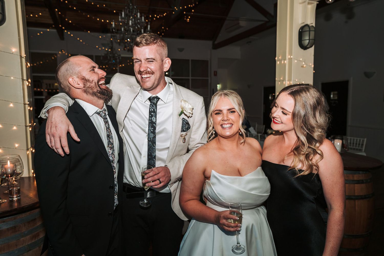 Group of wedding guests celebrating and laughing together at an indoor reception.