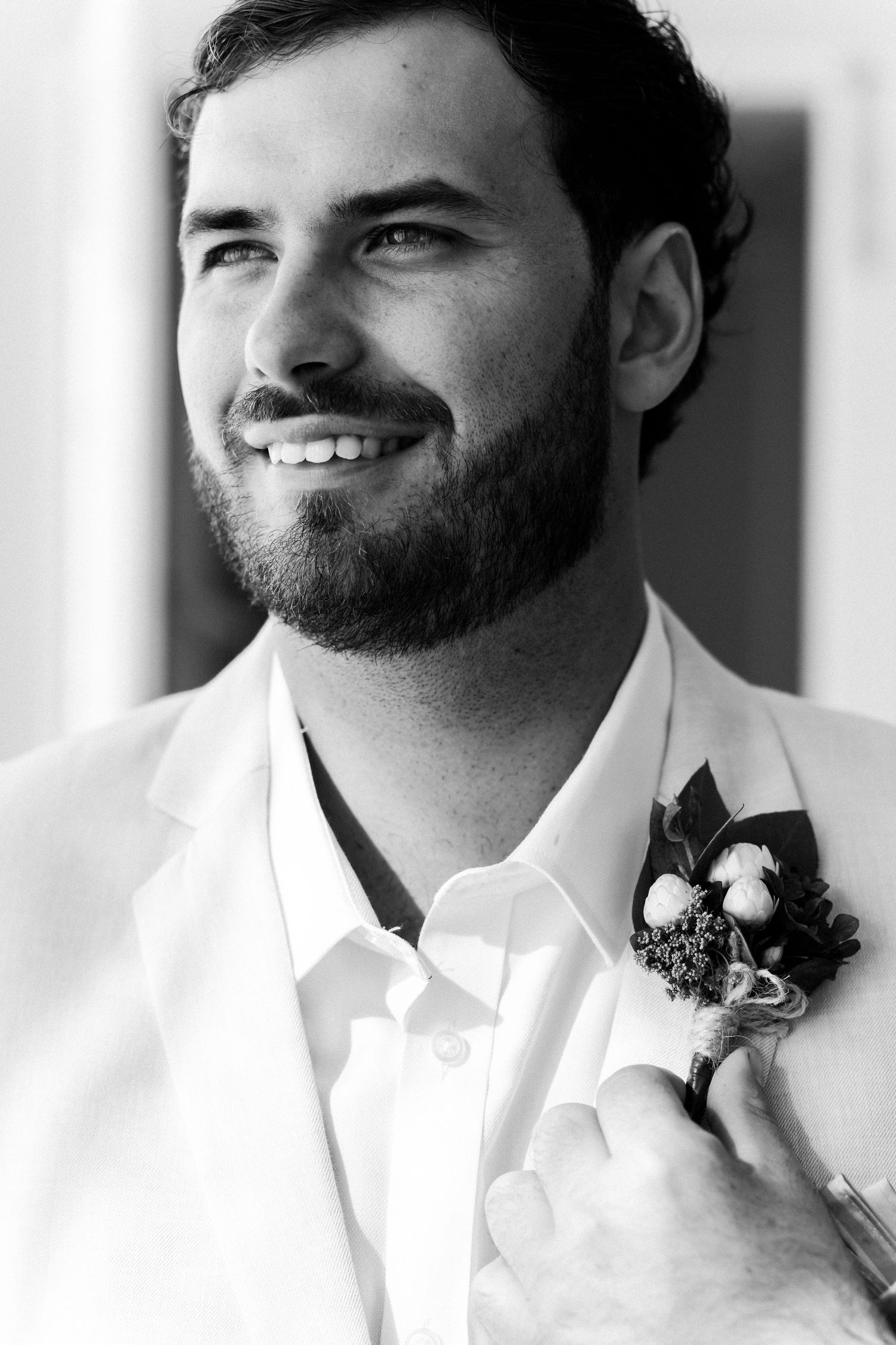 Black and white portrait of person wearing boutonniere and white shirt.