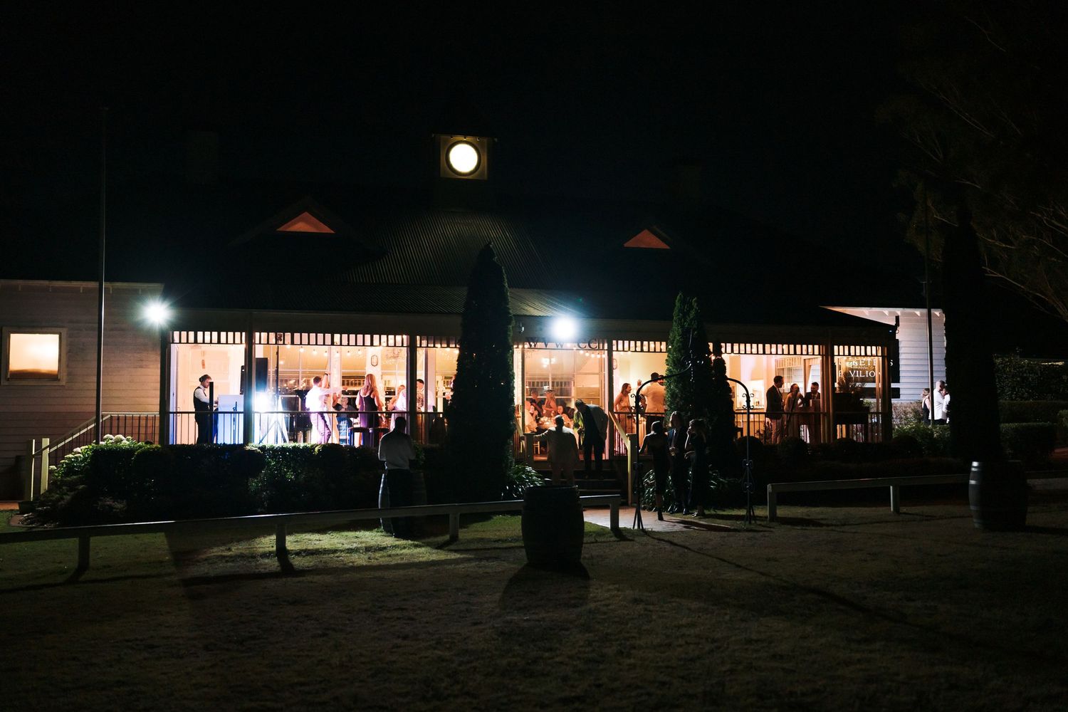 Wedding venue illuminated at night with full moon overhead as guests celebrate inside.