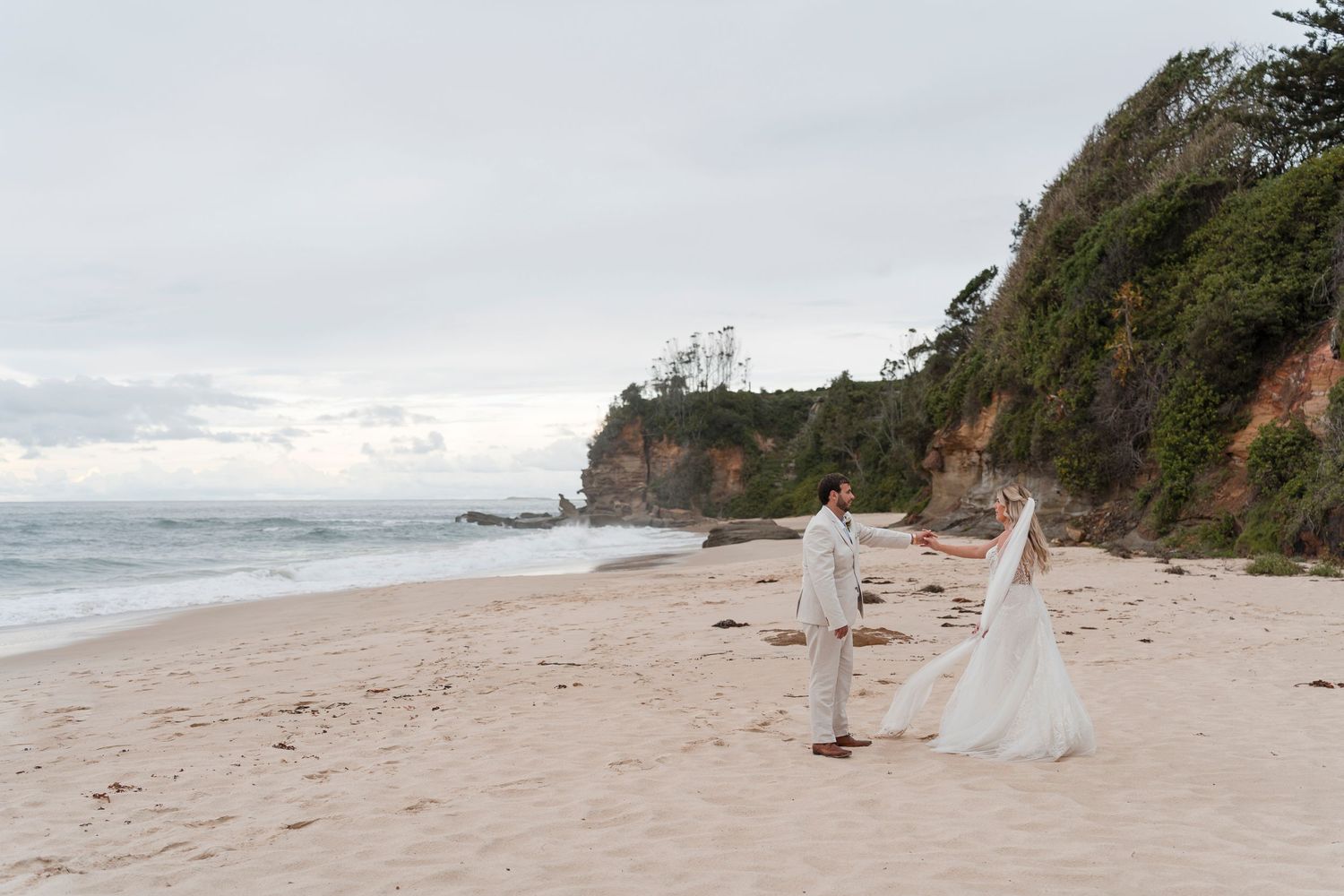 Beach wedding setup with white decorations along a scenic coastal cliff.