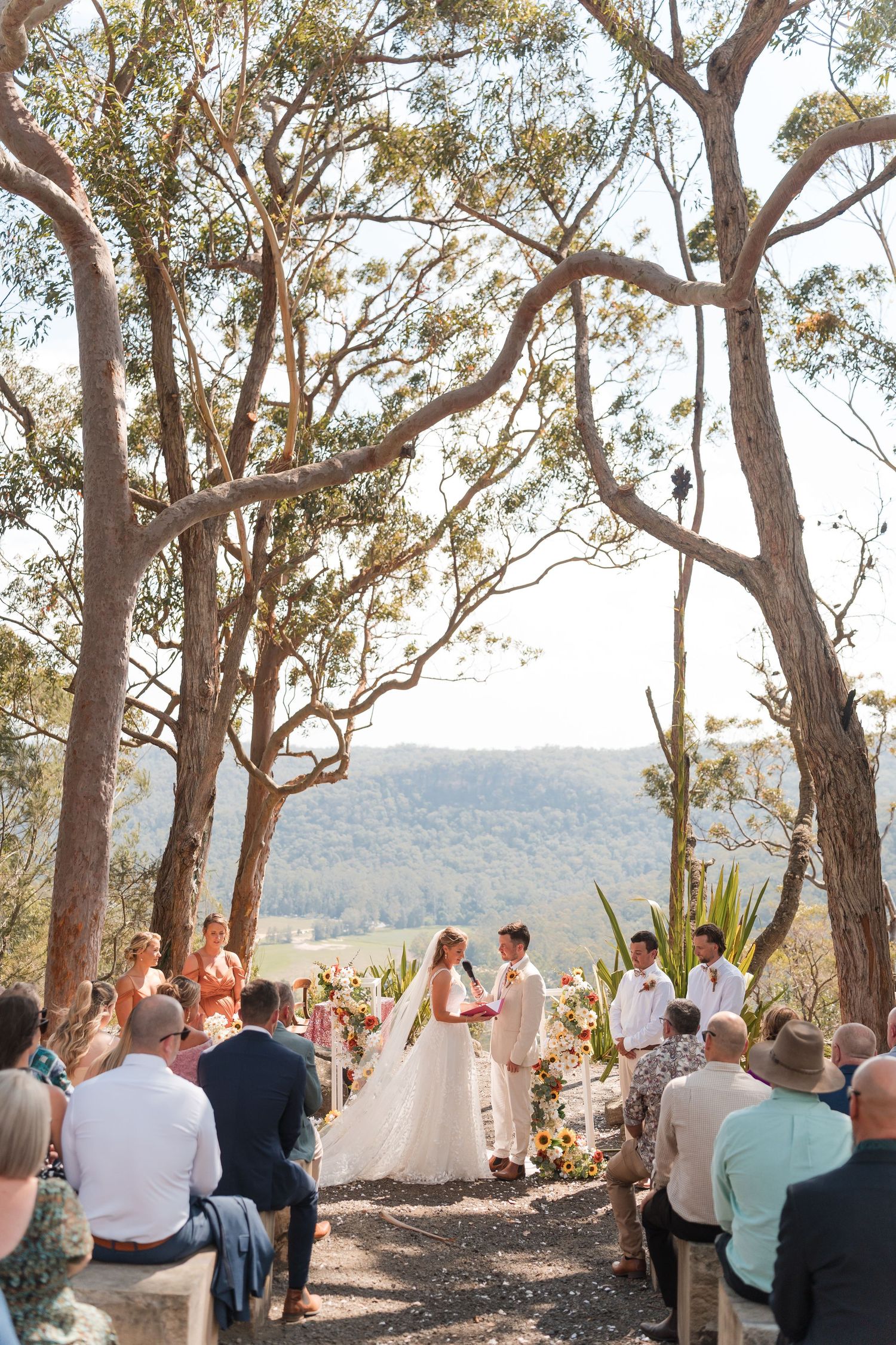 Outdoor wedding ceremony with couple at altar surrounded by eucalyptus trees and scenic mountain valley views.