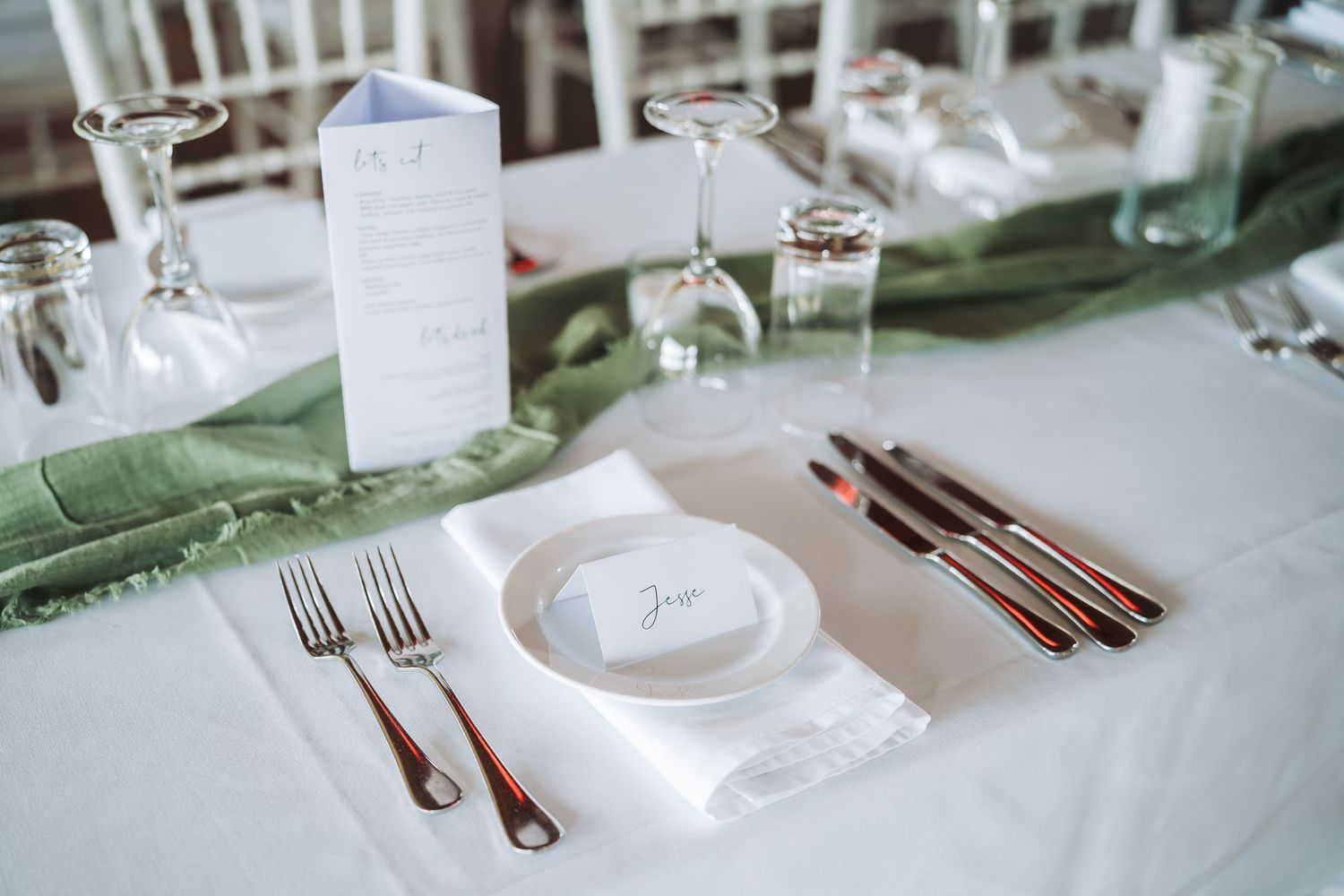 Elegant table setting with white linens, silverware, and mint green accents for a formal dining event.
