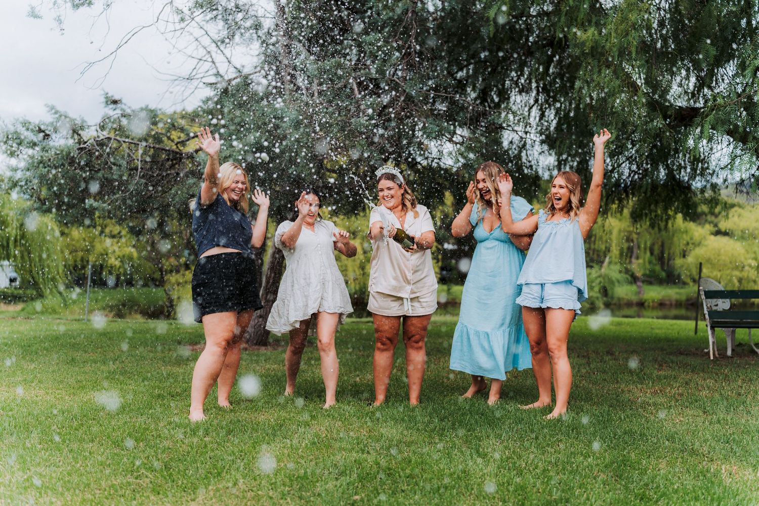 Group celebration outdoors with casual attire and drinks on sunny day.