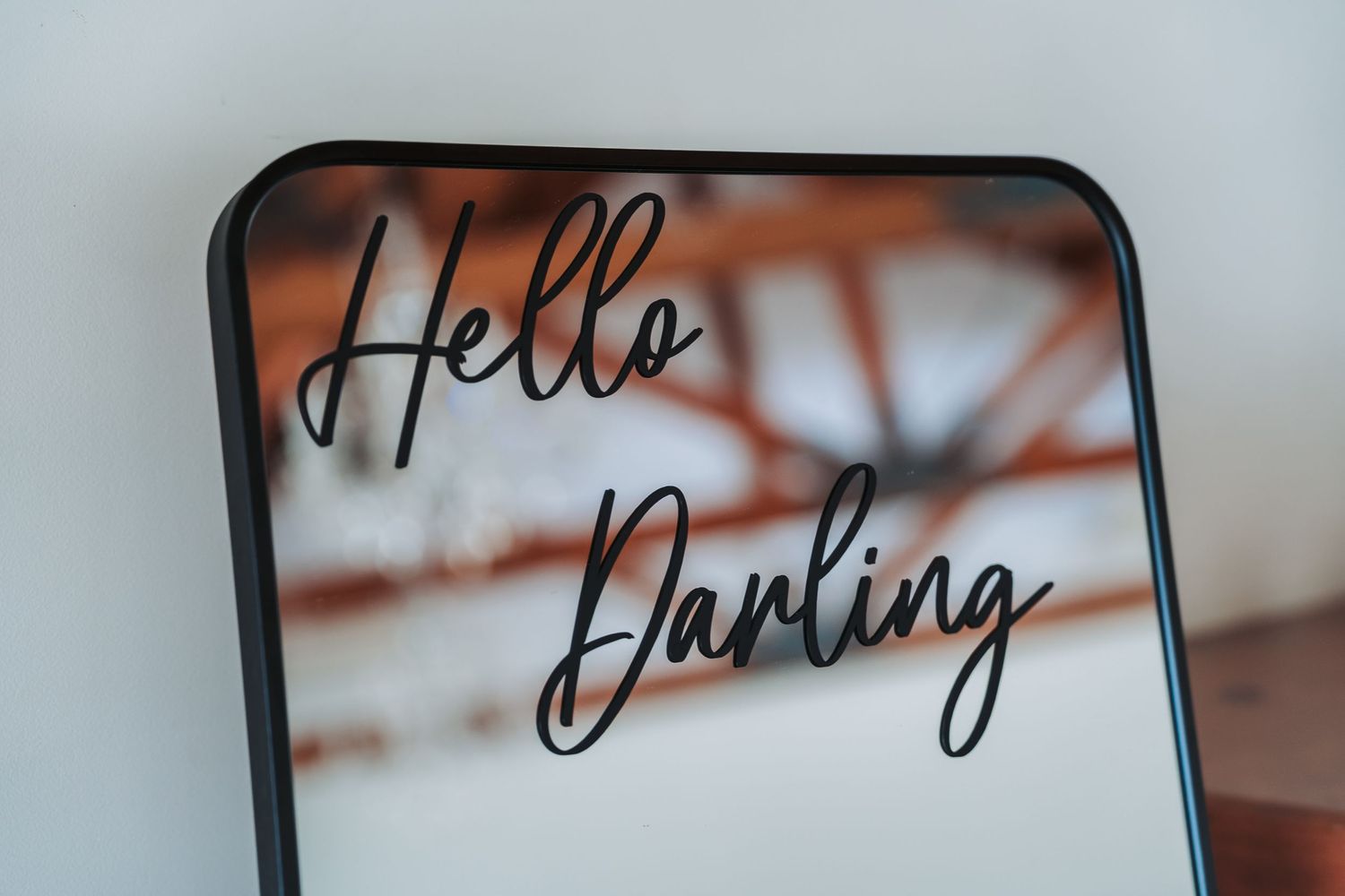 Close-up of mirror with 'Hello Darling' text in cursive writing against blurred background.