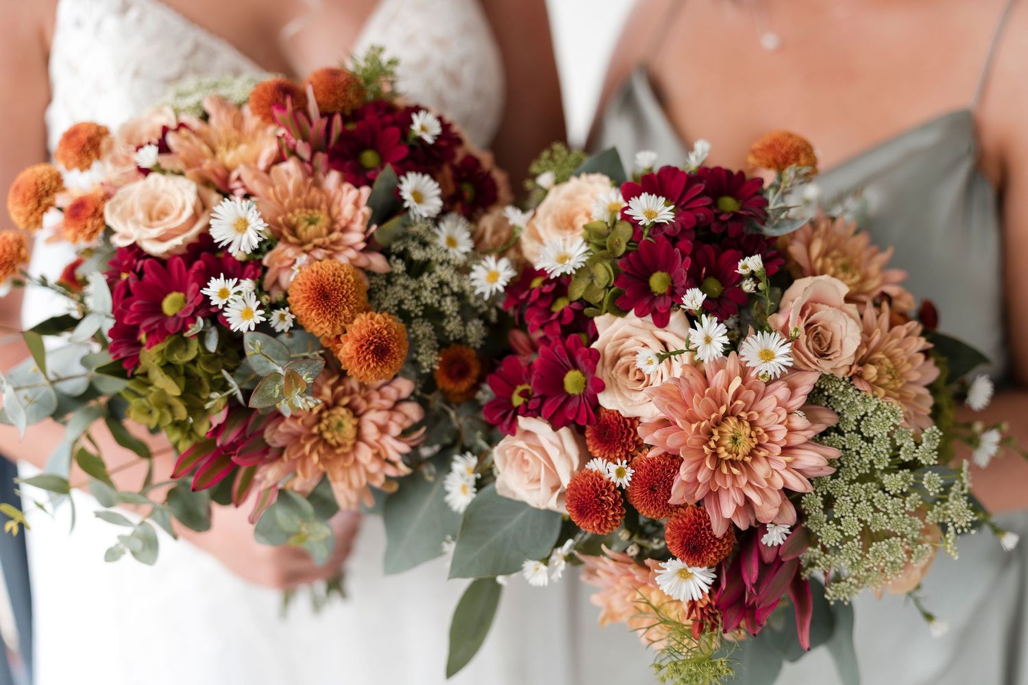 Vibrant wedding bouquets featuring pink, orange, and burgundy flowers with greenery.
