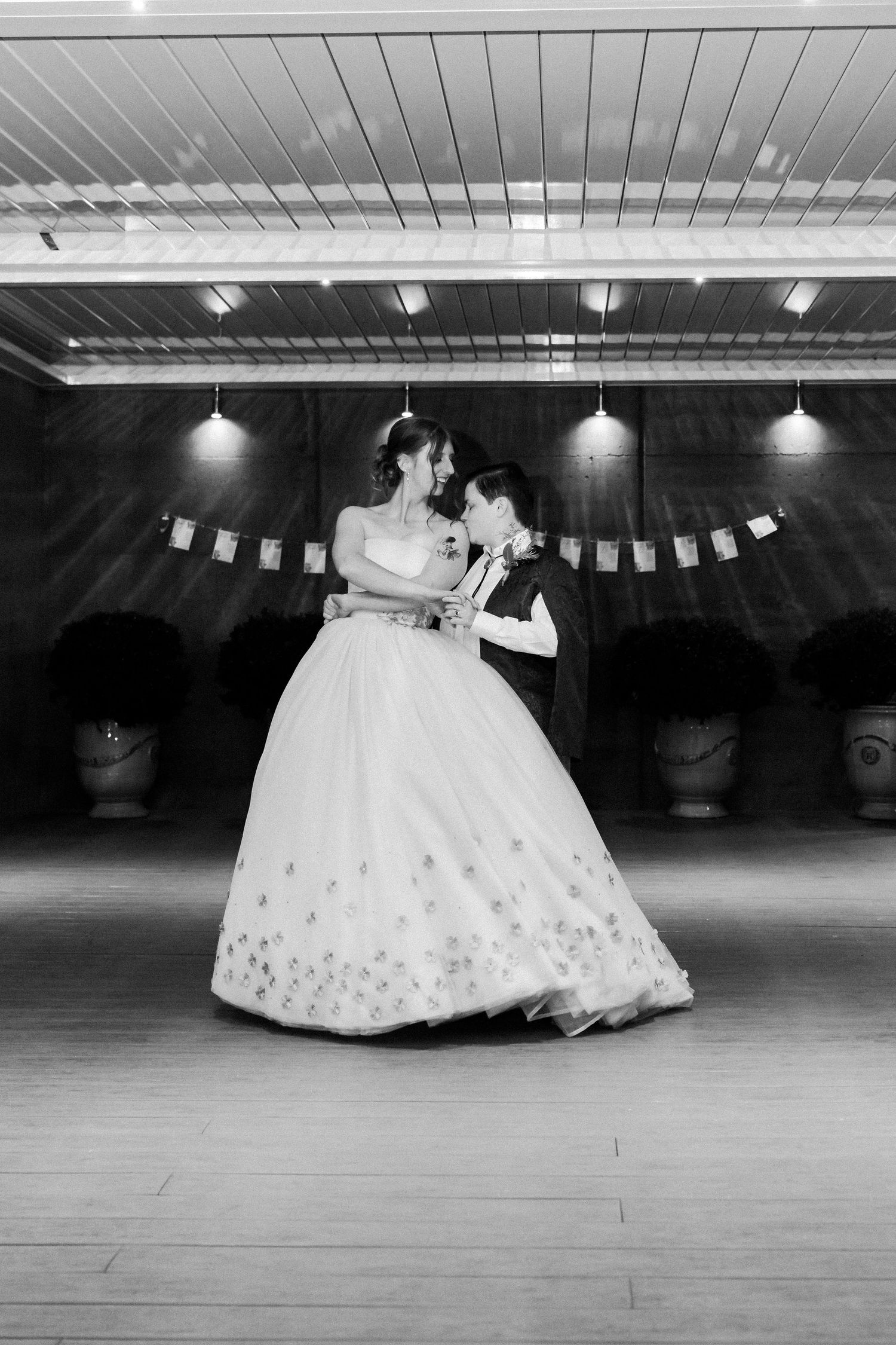 A romantic dance moment captured in black and white under decorative string lights.