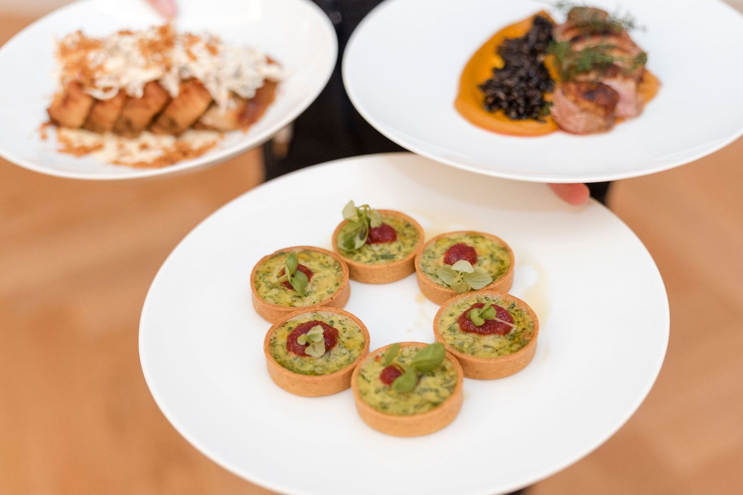 Circular arrangement of pinwheel appetizers garnished with green herbs on a white plate.