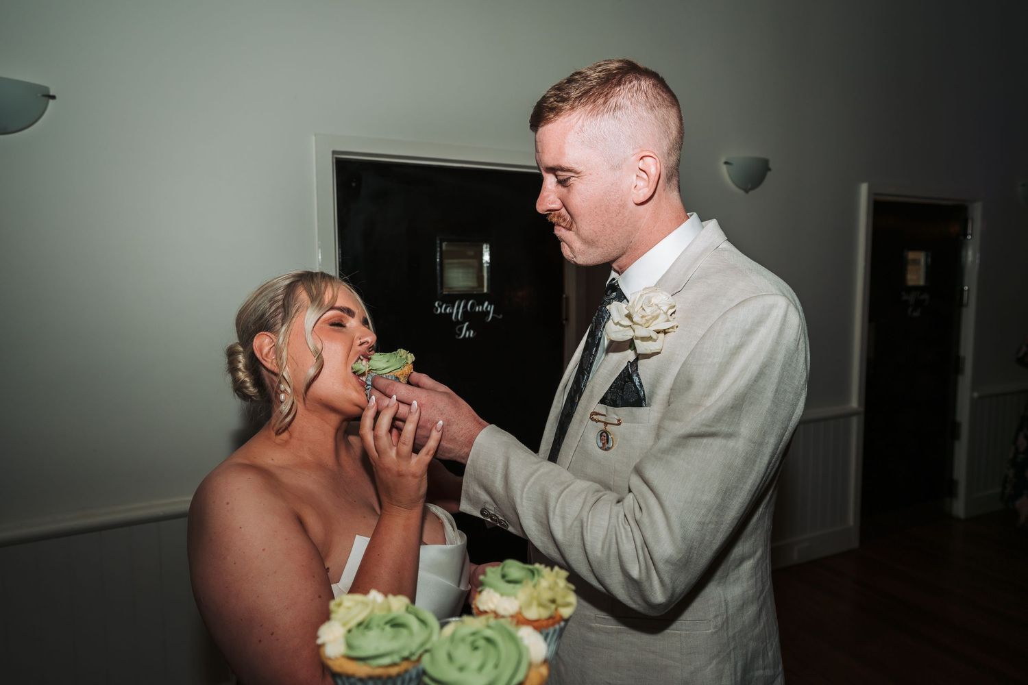 Couple sharing a playful cake-feeding moment during their wedding reception.