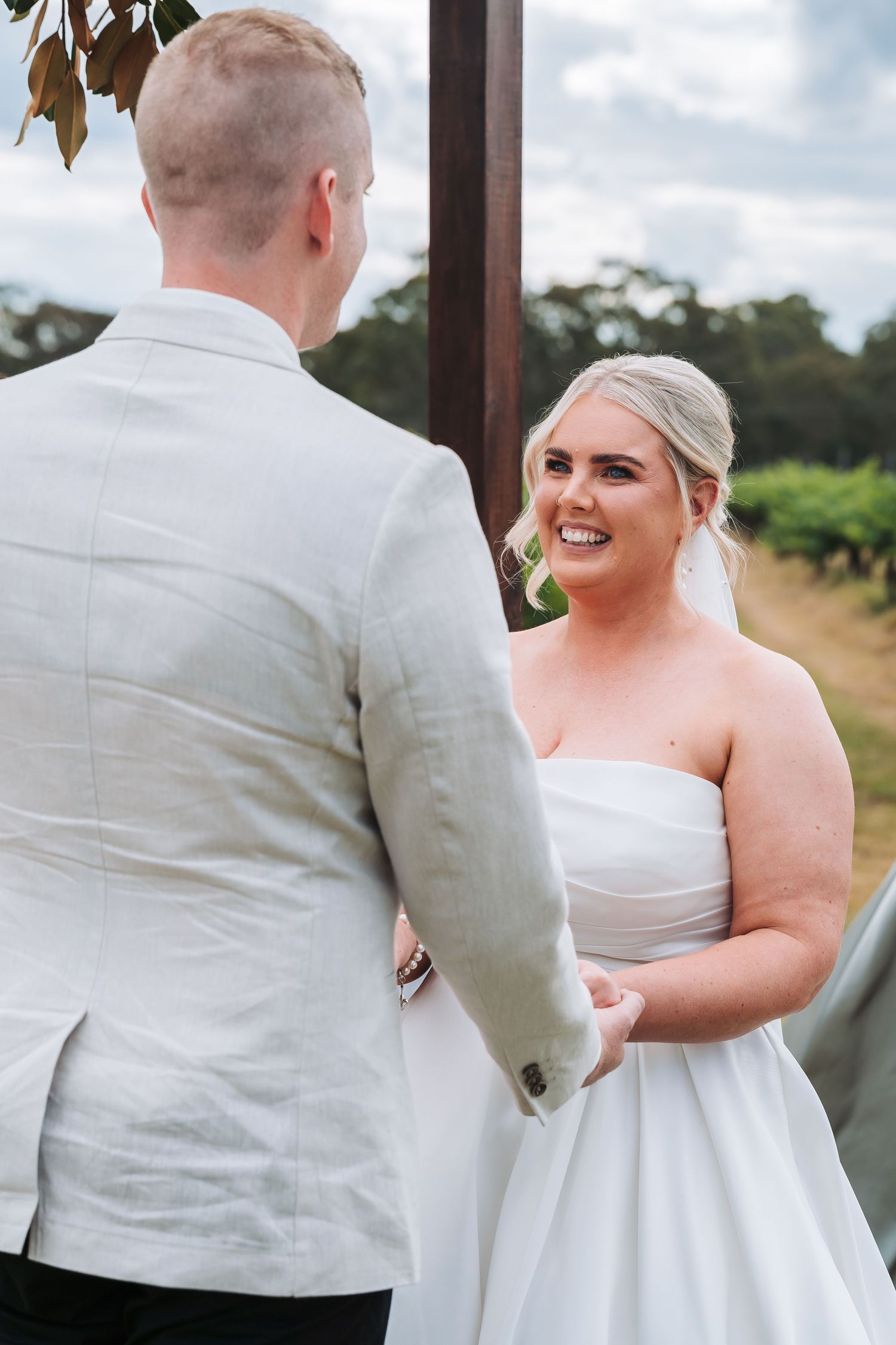 A happy couple shares a joyful moment on their wedding day, with the bride wearing a strapless white gown.