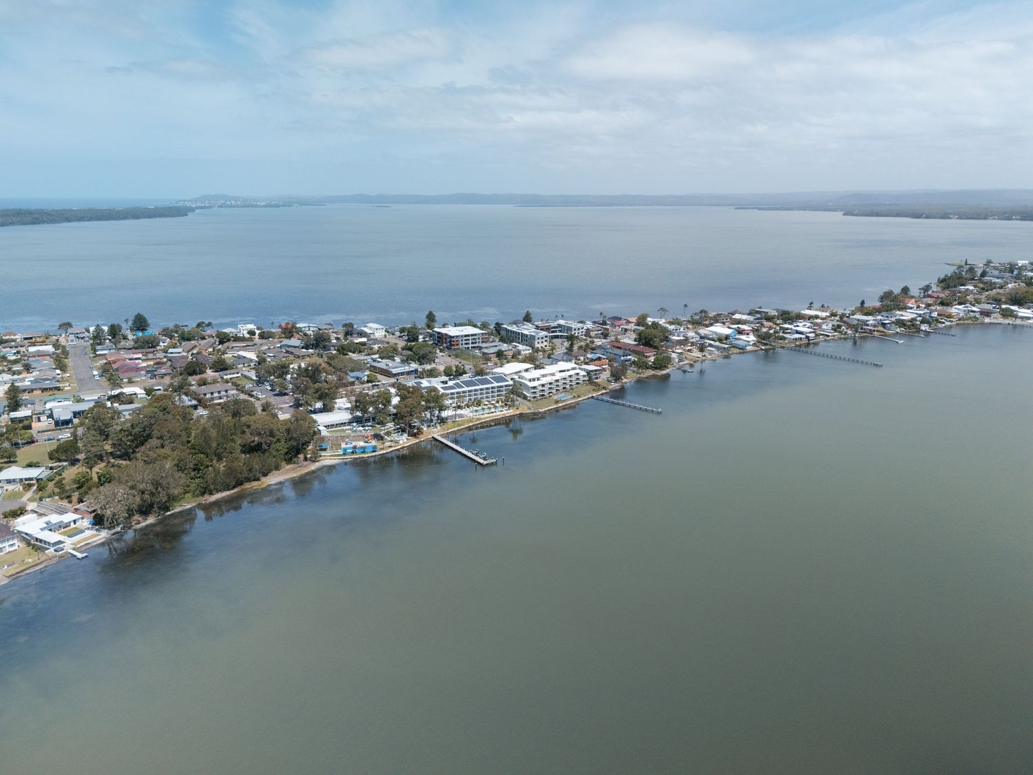 Aerial view of a coastal town nestled between calm waterways under a partly cloudy sky.