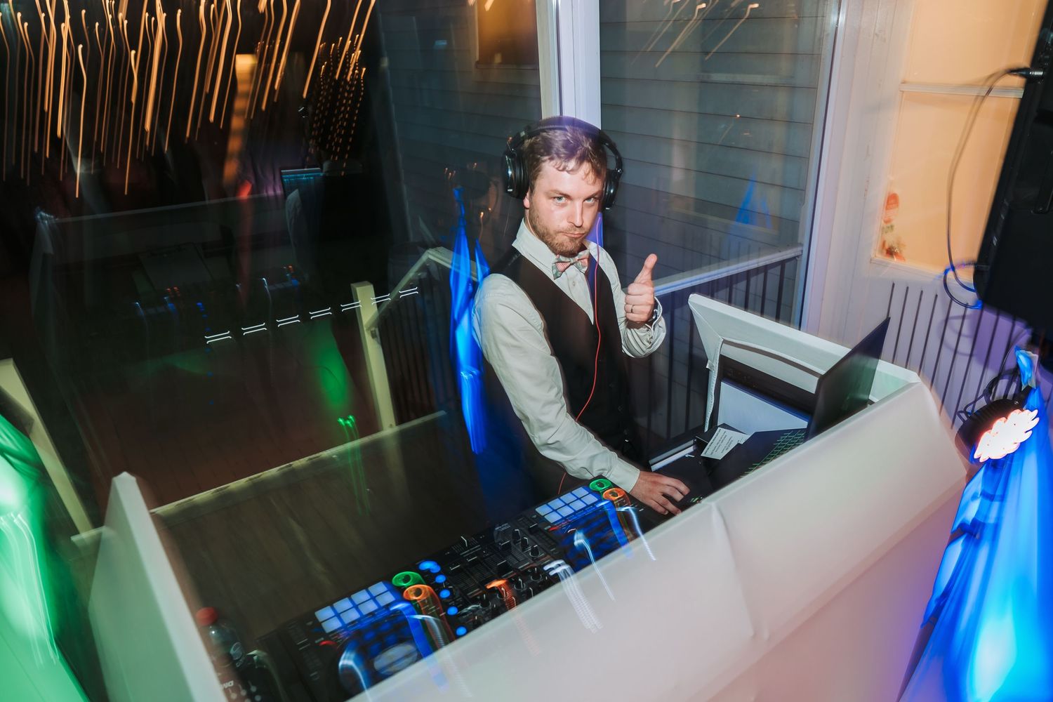 DJ performing at a party setup with blue and green lighting effects.