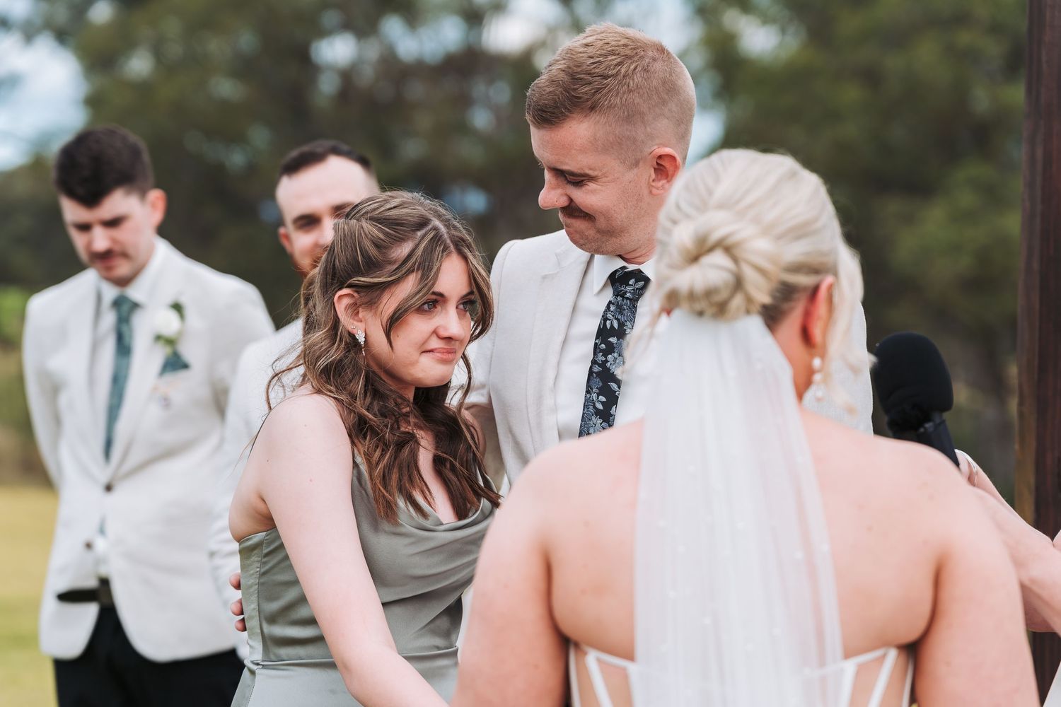 Wedding party members share a candid moment outdoors during the celebration.