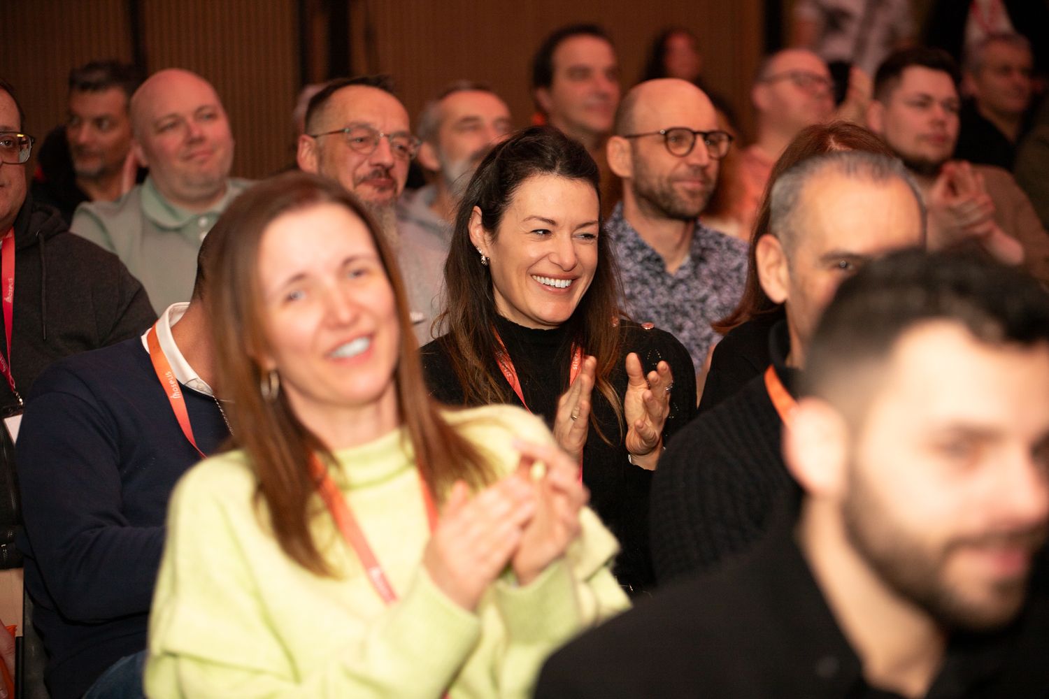 Des membres heureux du public souriant et applaudissant lors d'une conférence professionnelle.