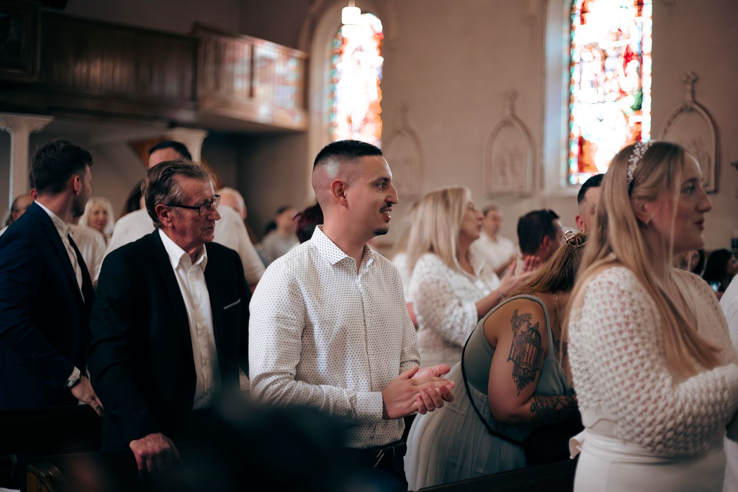 Congregation gathered in church during religious ceremony with stained glass windows.