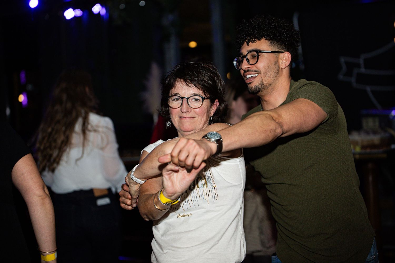 Two people dancing and smiling together at a lively nighttime party event.