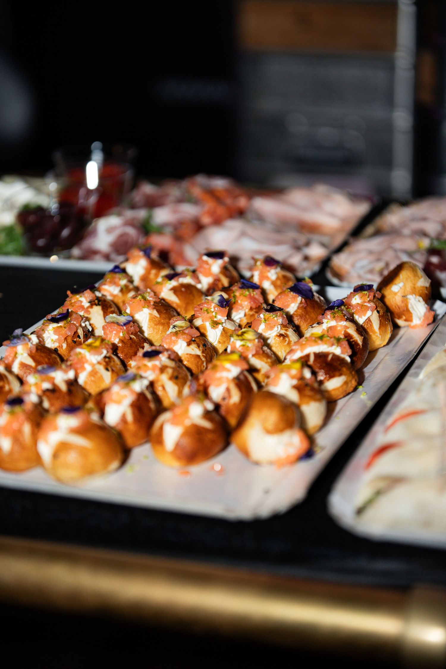 Elegant catering display of gourmet sliders and appetizers on trays at an event.