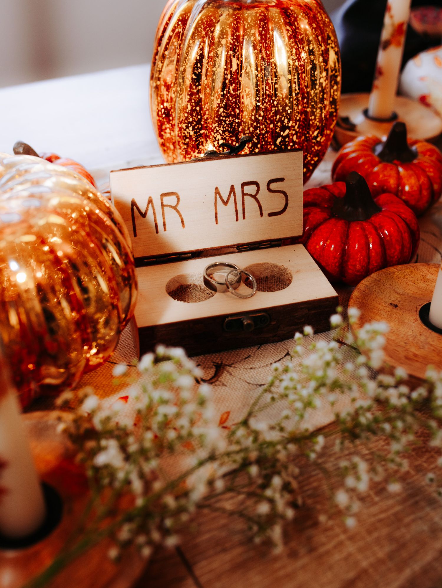 Wedding rings in wooden Mr and Mrs box surrounded by autumn pumpkin decorations.