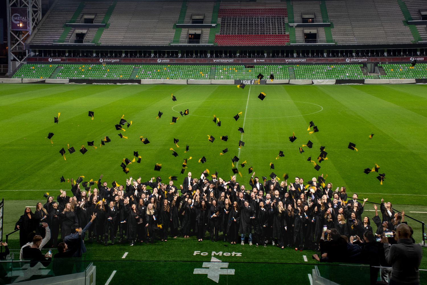 Graduates tossing caps in stadium during 2025 graduation ceremony.