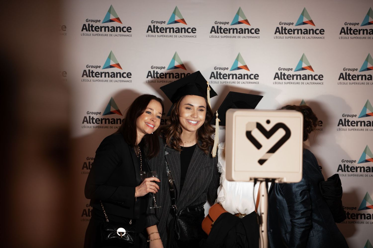 Two young women posing at Groupe Alternance graduation event photo backdrop.