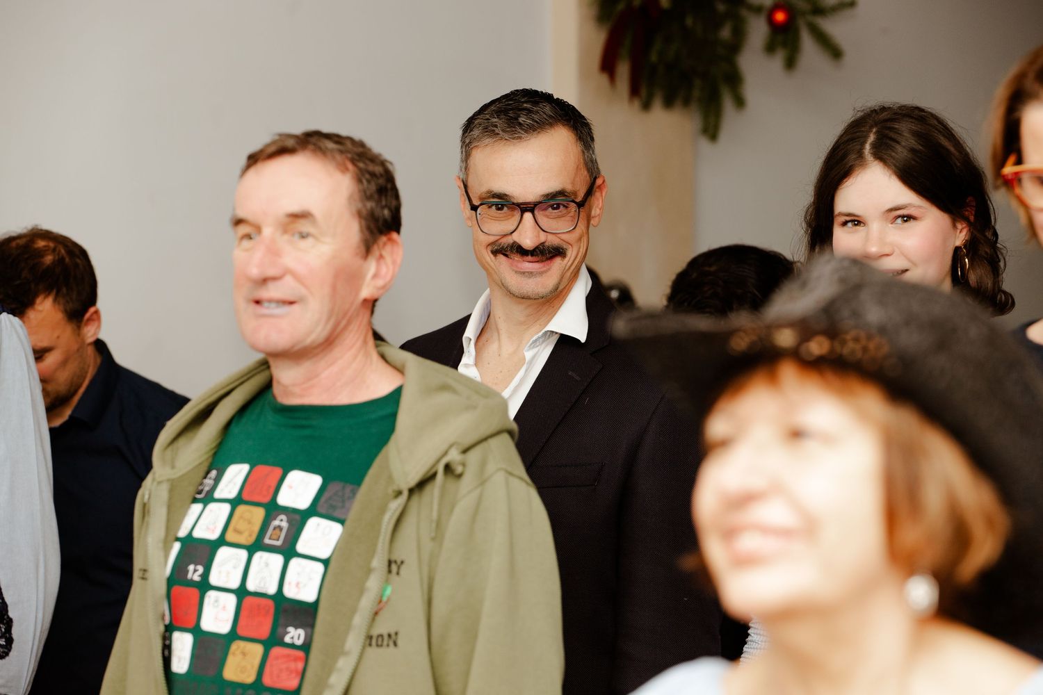 Group of adults gathered together smiling at a festive Christmas holiday event.
