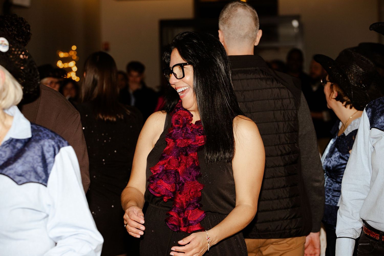 Woman in black outfit with red floral accessory dancing at a holiday party.