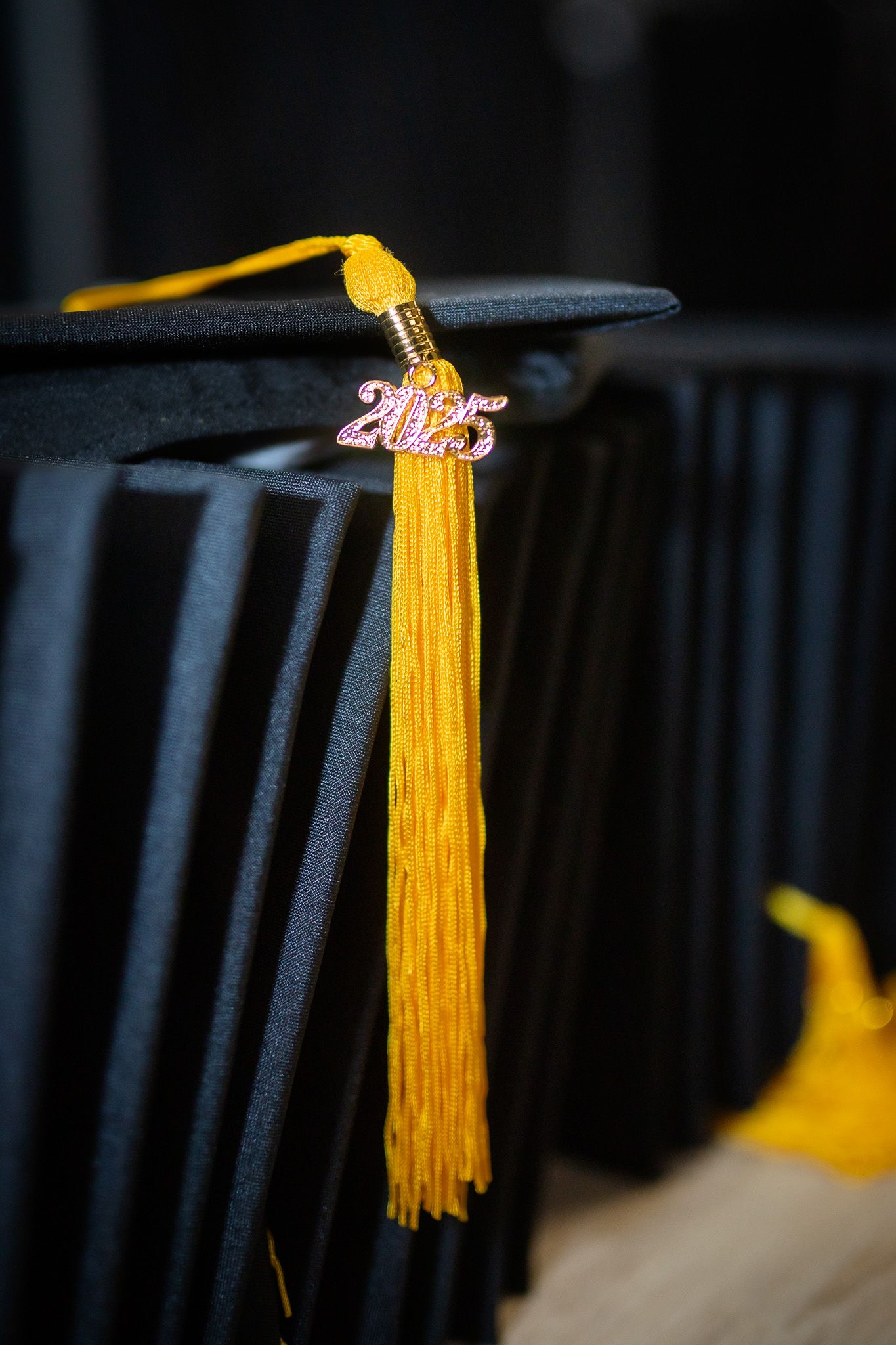 Black graduation cap with gold tassel and 2025 charm closeup.