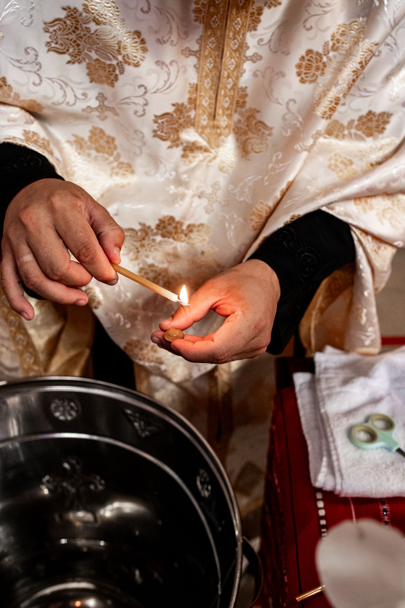 Priest in ornate gold vestments lighting a match during a religious wedding ceremony ritual.