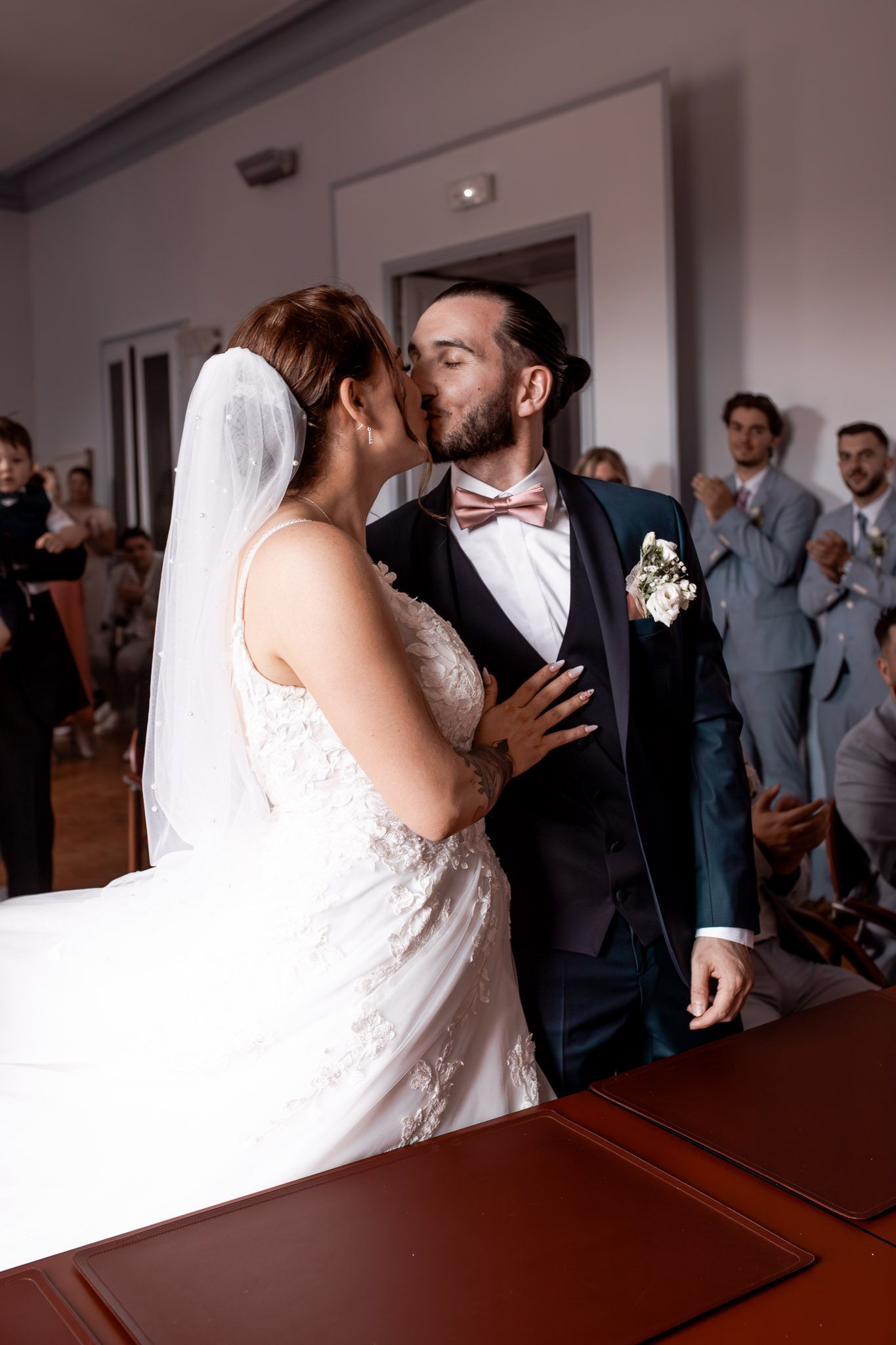 Bride and groom sharing their first kiss at the altar during their wedding ceremony before applauding guests.