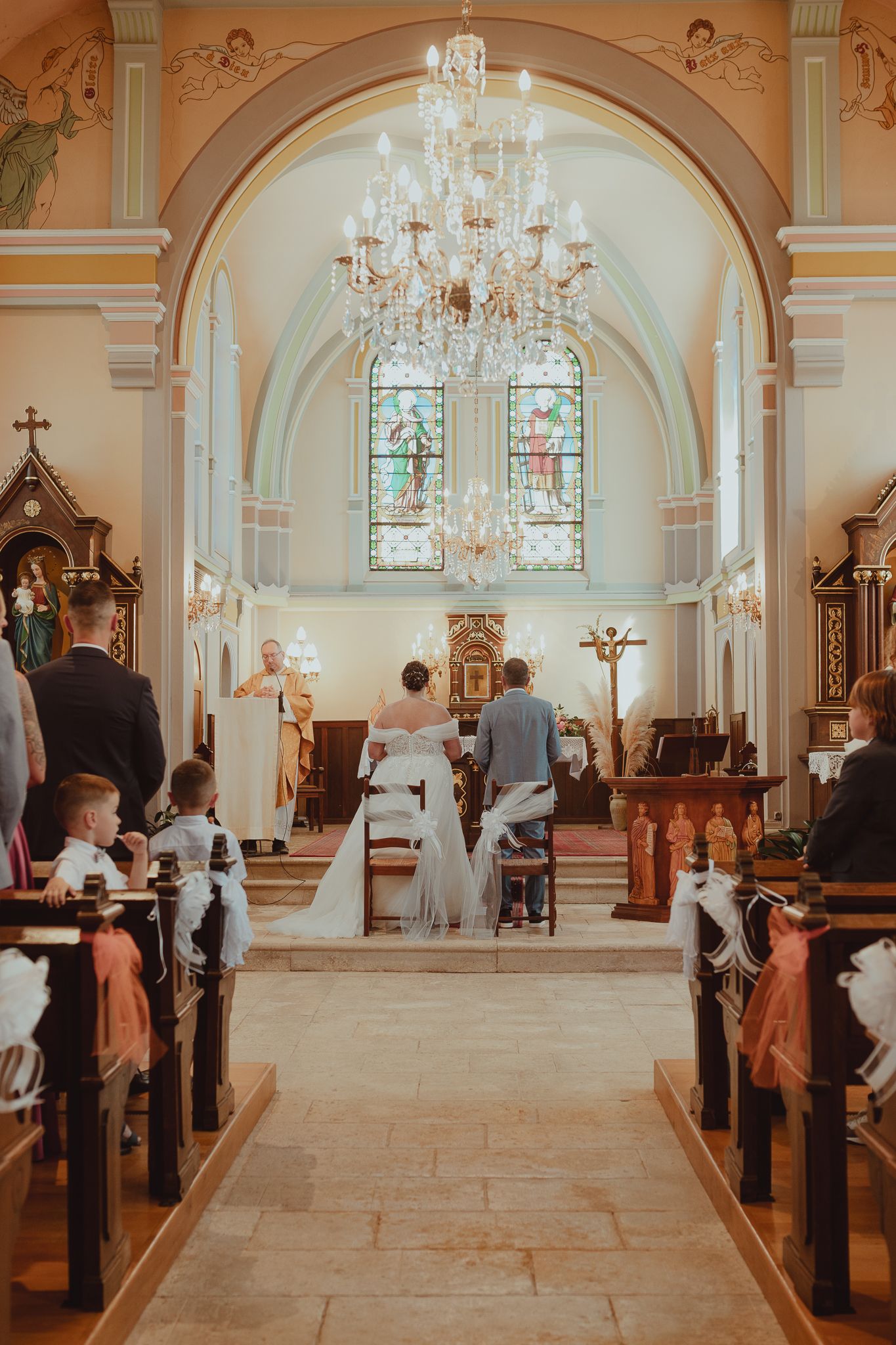 Bride and groom at the altar of an ornate church during their wedding ceremony.