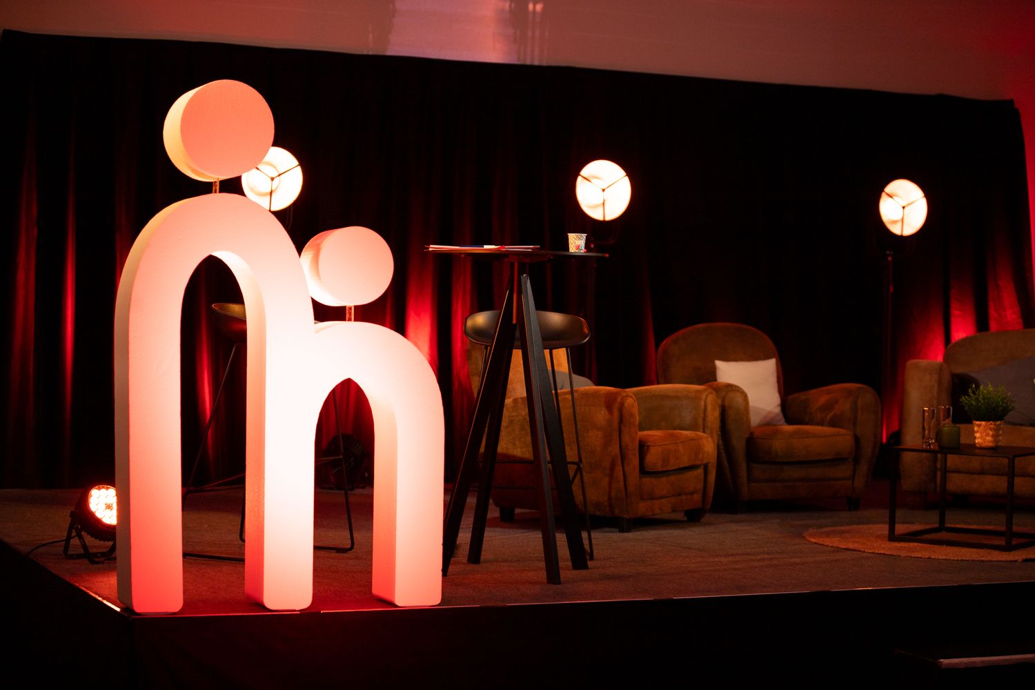 Étail de scène en arc éclairé avec des lumières sphériques lumineuses et des fauteuils confortables sur une scène de conférence spectaculair