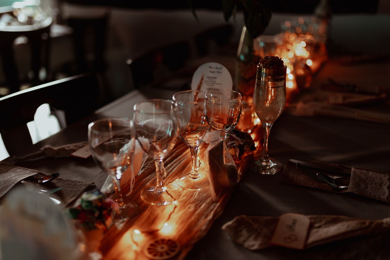 Elegant dinner table set with wine glasses and warm candlelight for a formal event.