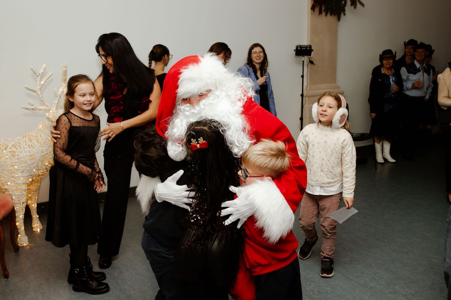 Children hugging Santa Claus at a festive Christmas holiday party celebration.