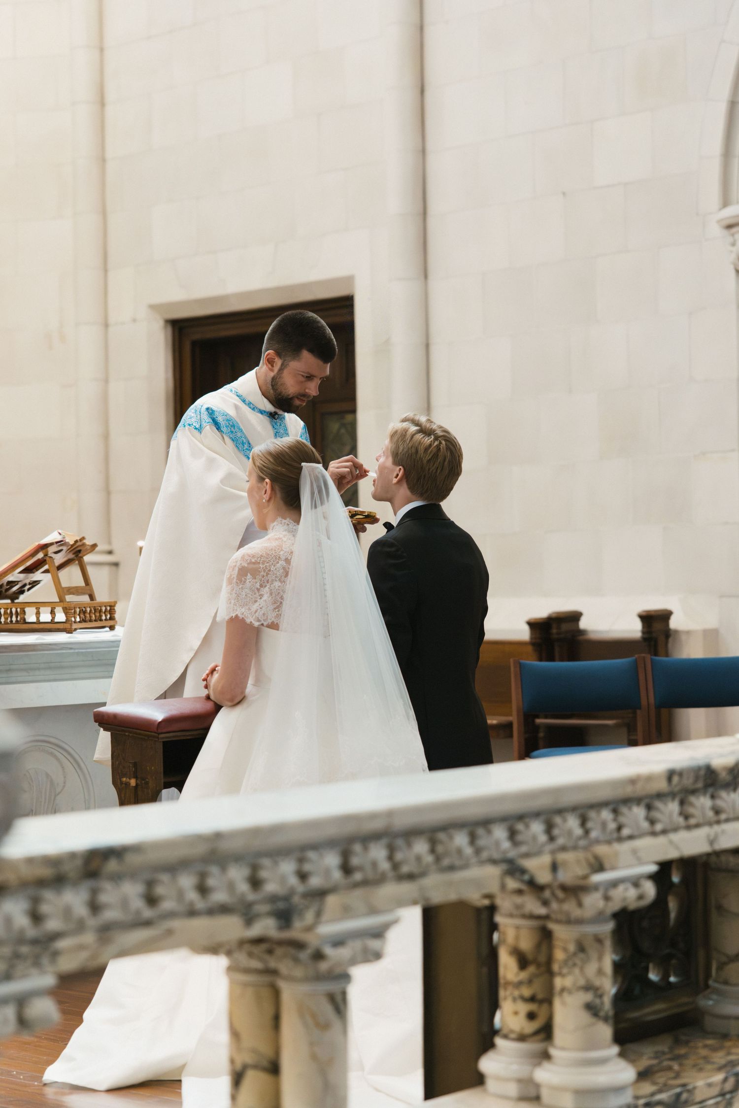 Priest blessing bride and groom during a traditional Catholic wedding ceremony at the church altar.