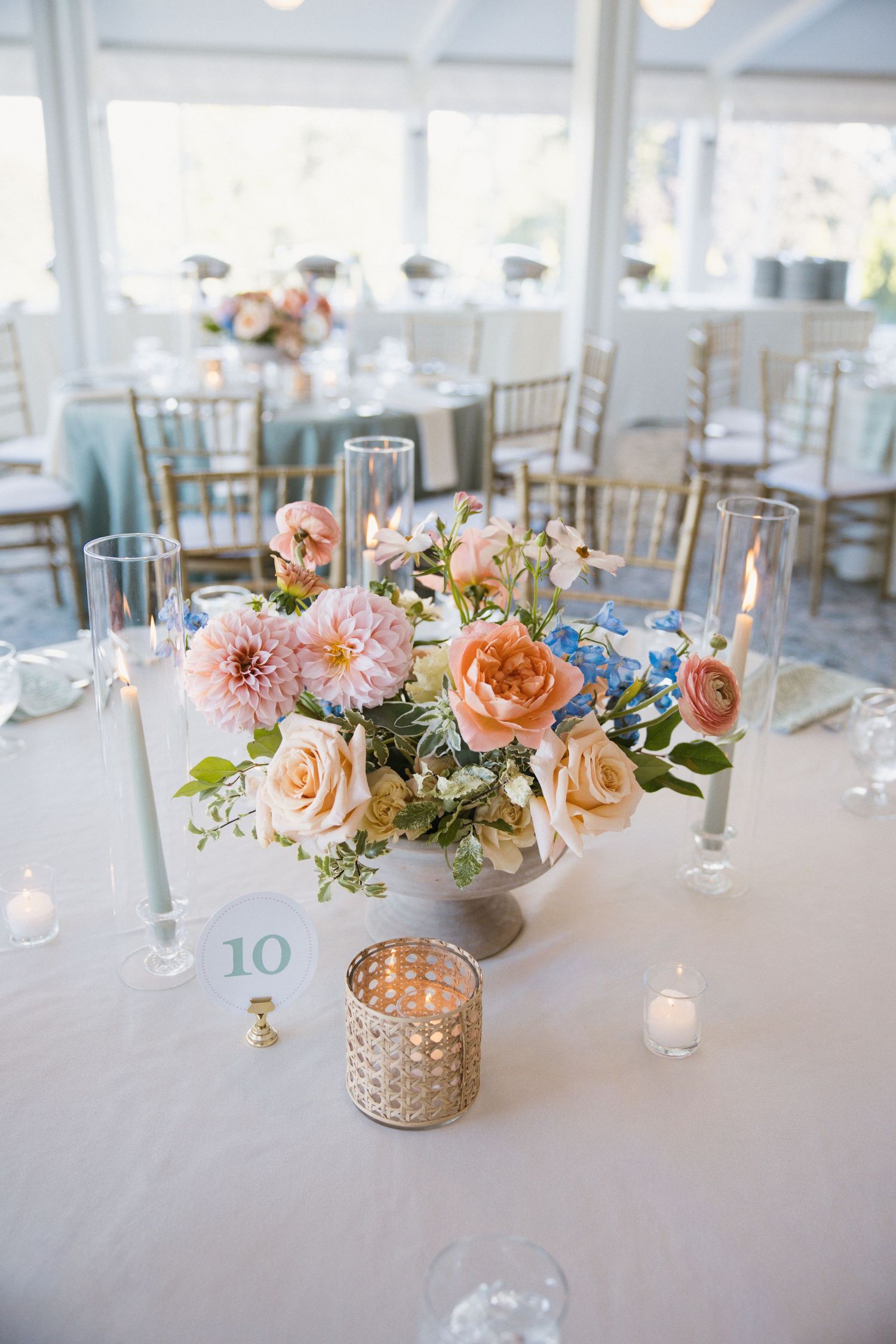Pastel floral centerpiece with pink dahlias and roses on reception table numbered ten.